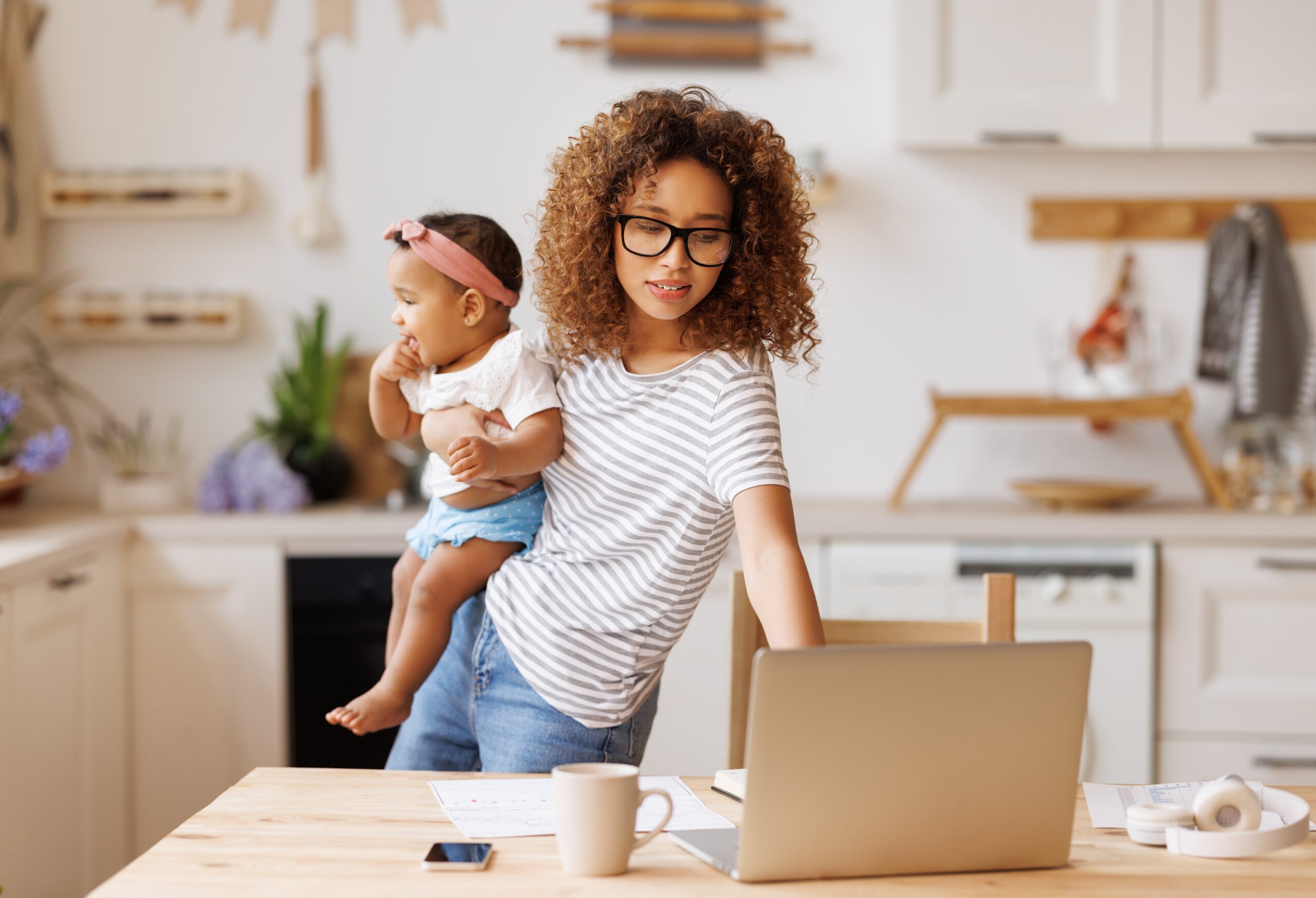 A multitasking mother holding her baby while working.