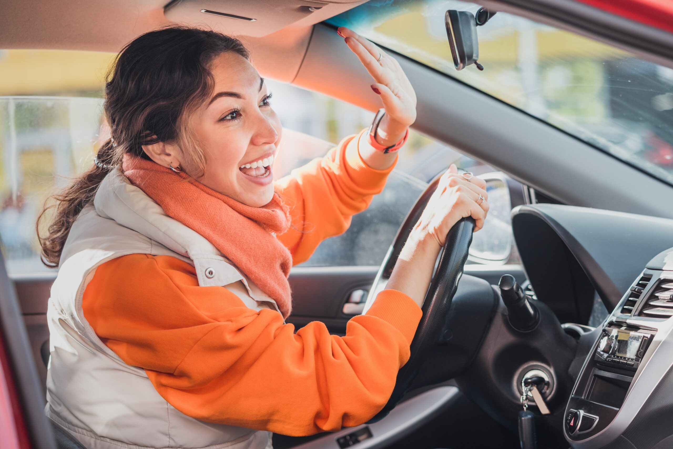 A polite female driver raising her hand as a sign of respect to a pedestrian.