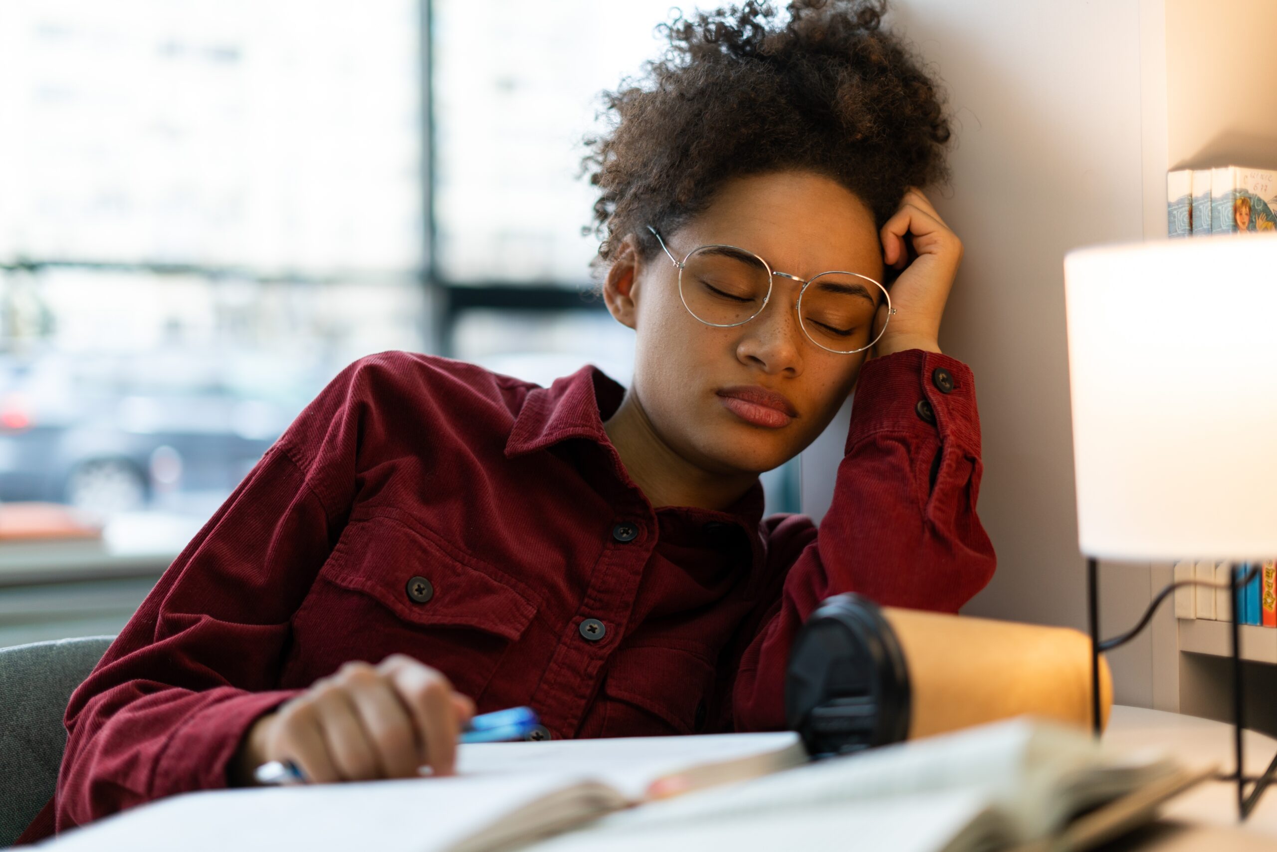 Exhausted woman asleep with her books on the table.