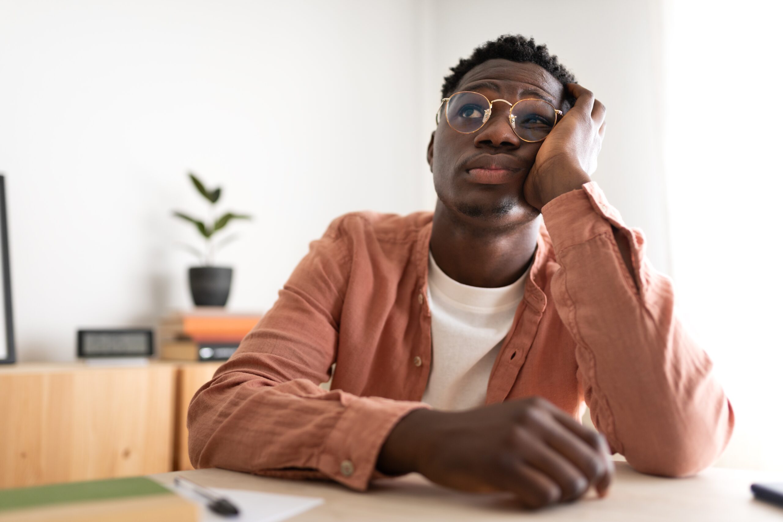 A man sitting at his desk feeling bored with his colleagues.