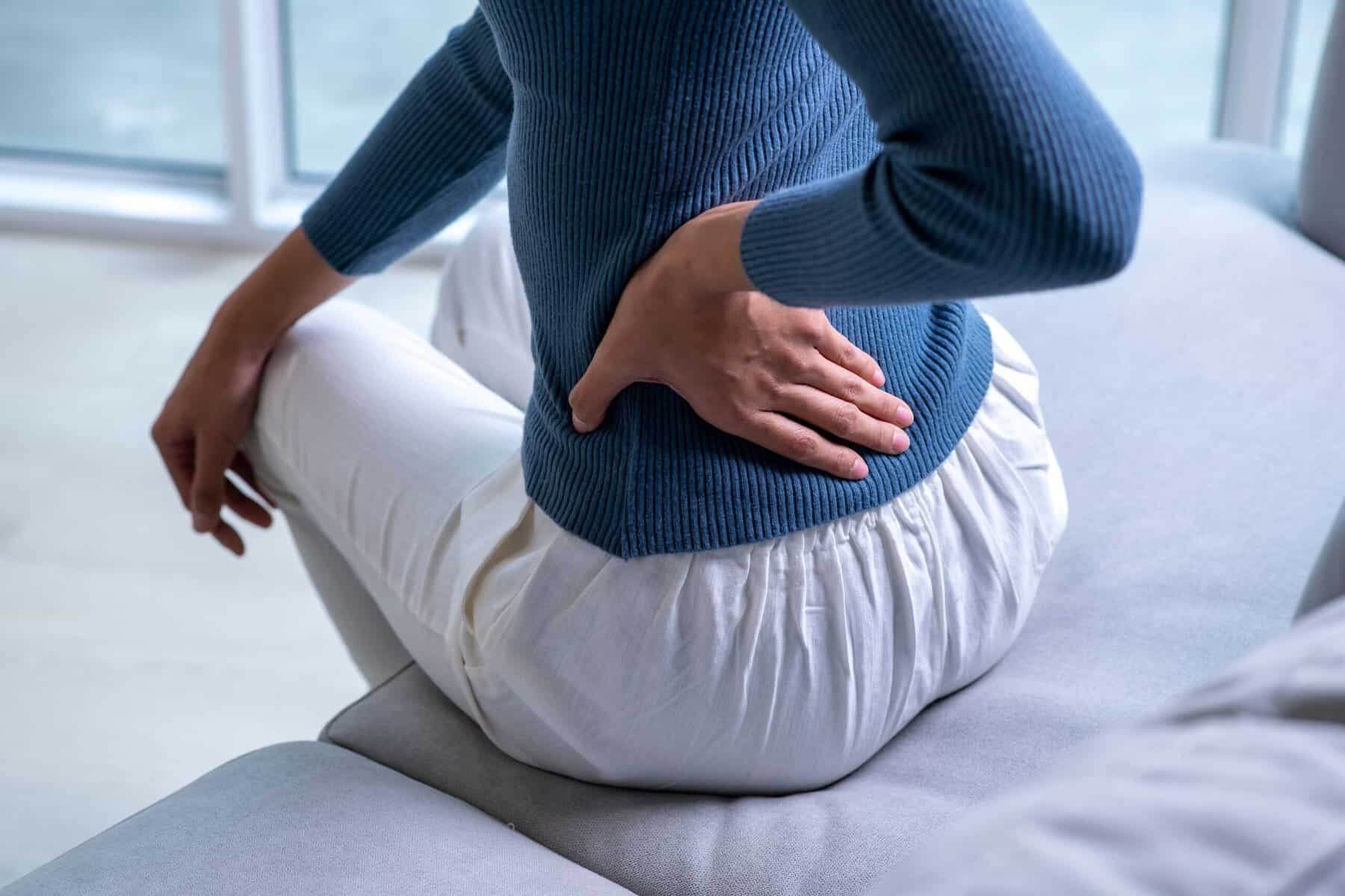 Woman suffering from a back ache on the sofa.