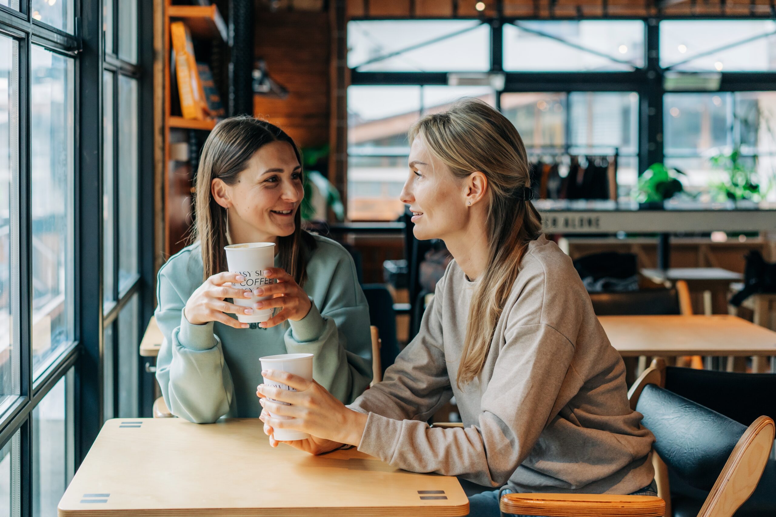 Two female friends catching up at a cafe over coffee.