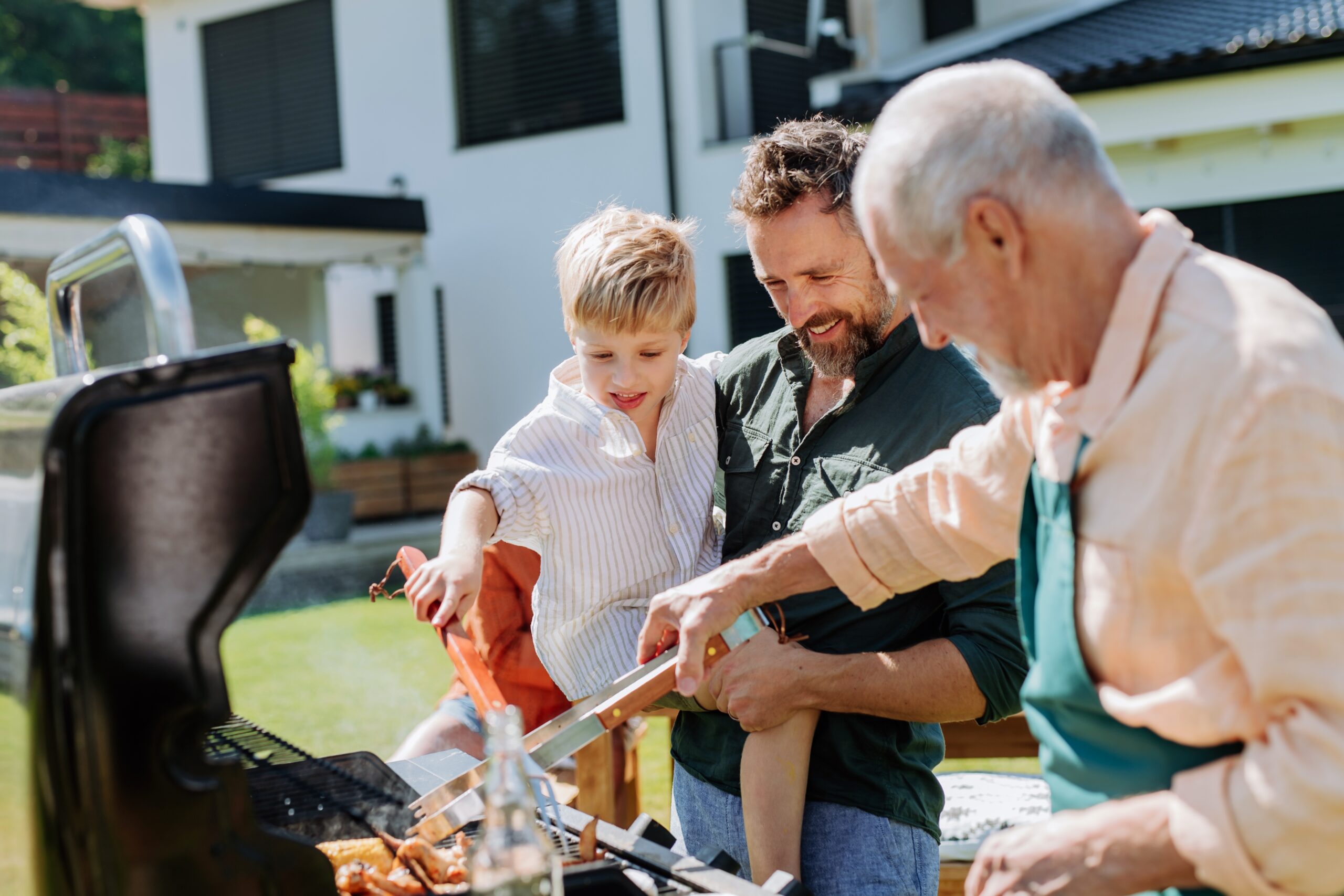 Multi generation family grilling outside in the backyard in summer.