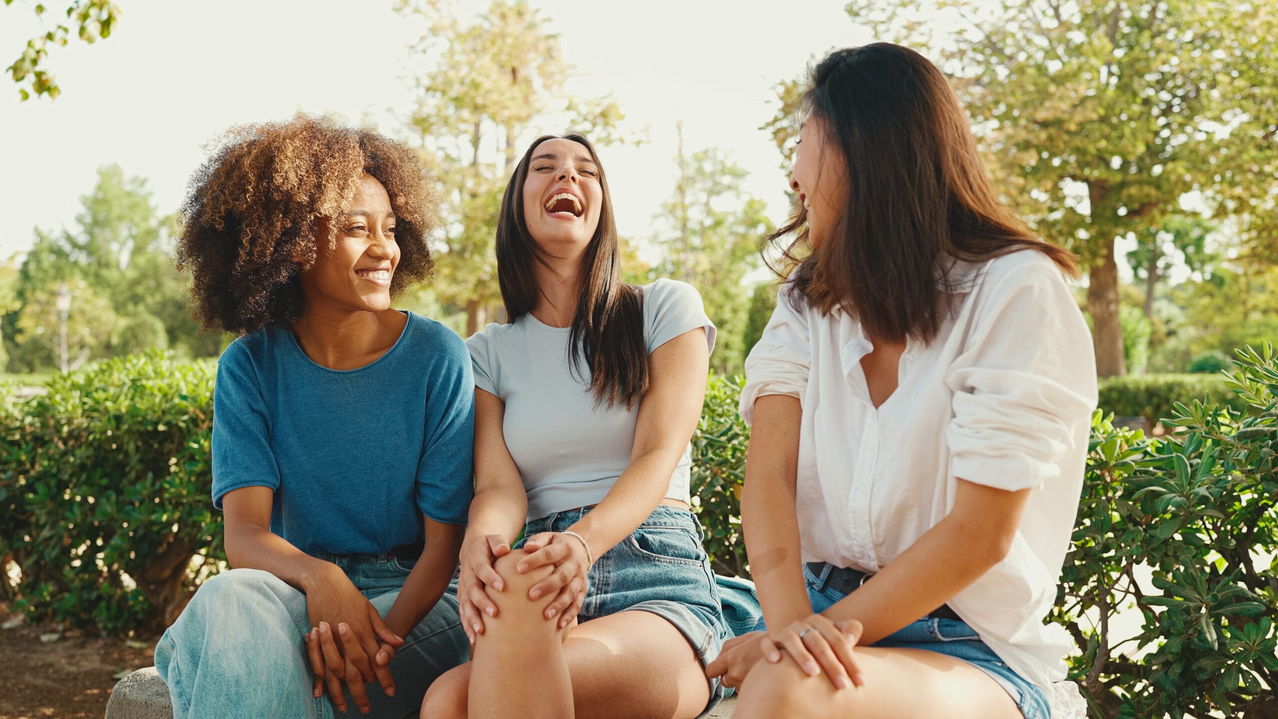 Three friends laughing together outside.