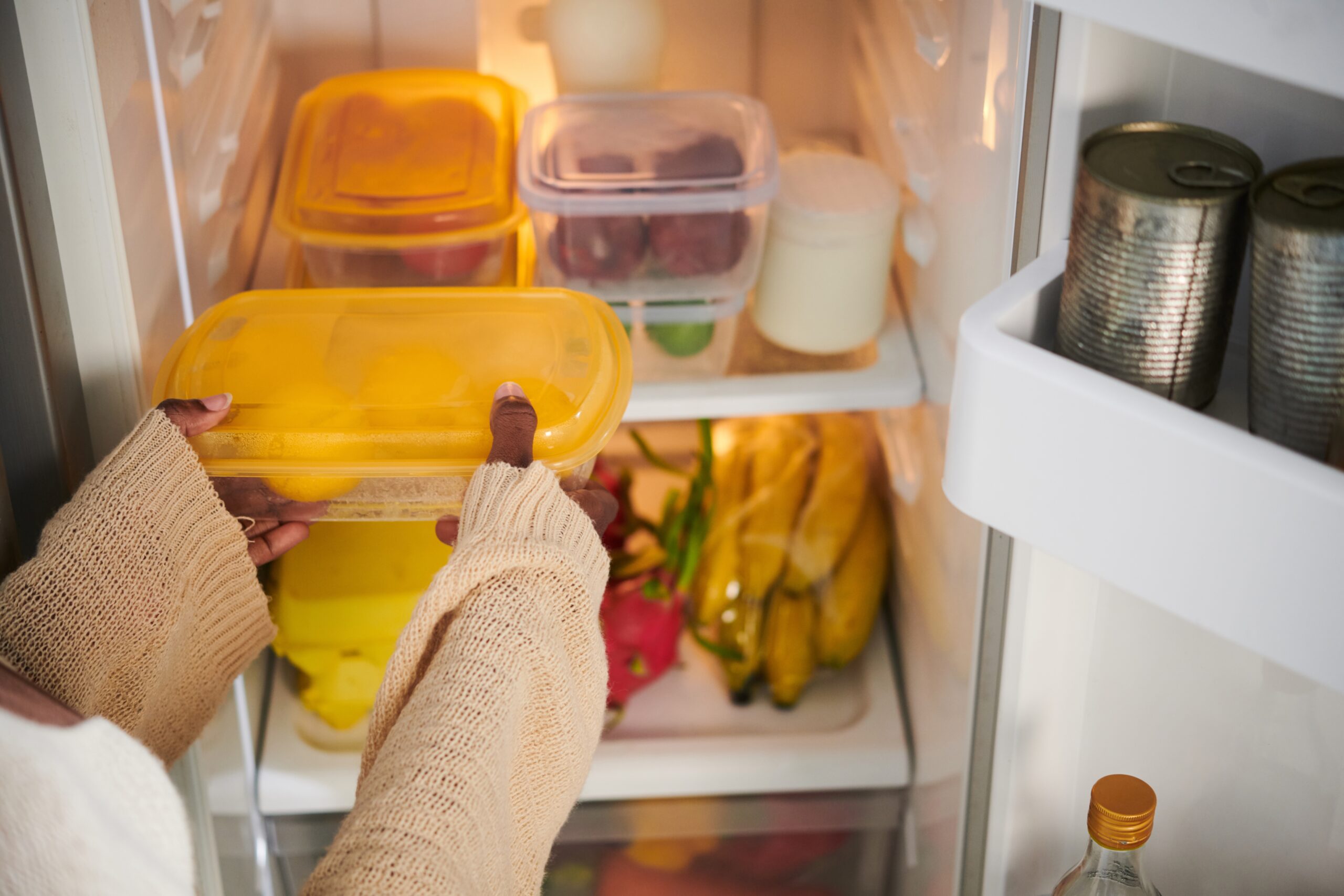 A woman storing leftovers in the refrigerator.