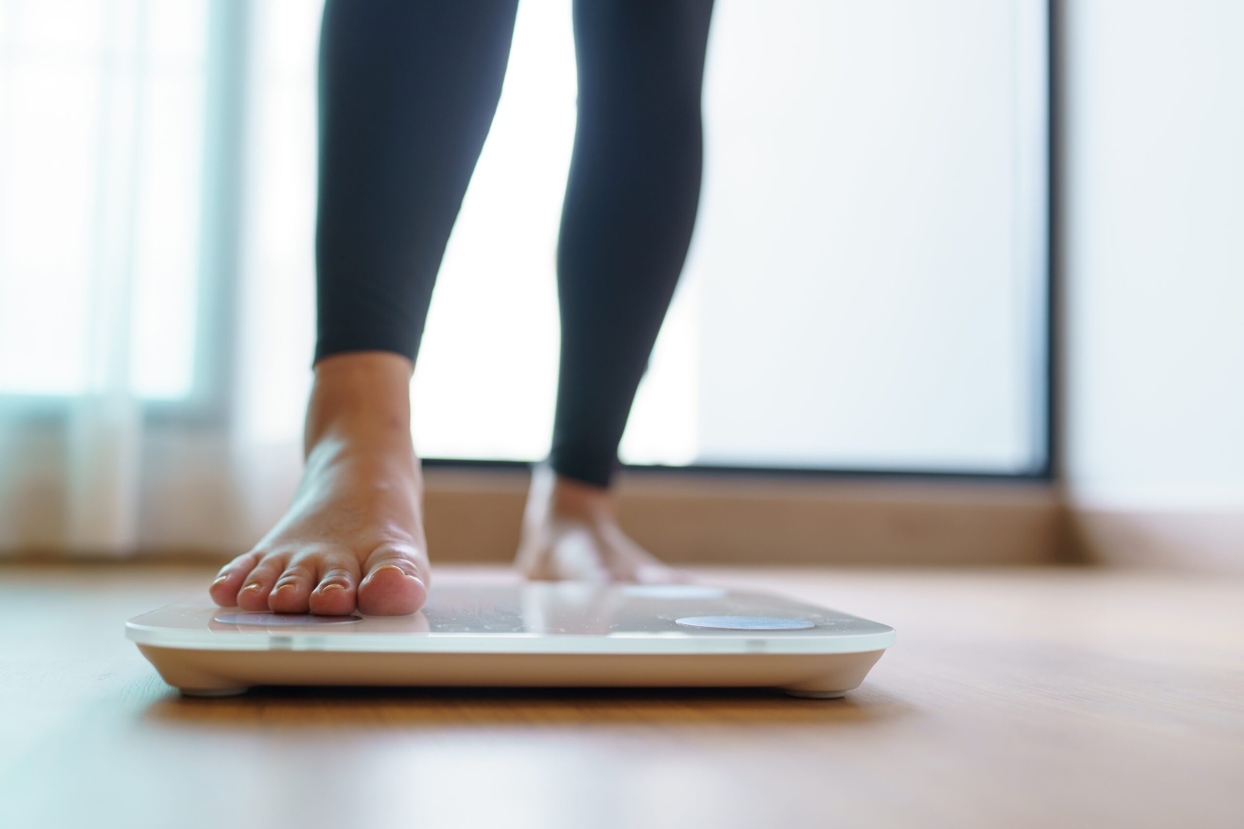 A woman stepping on the scale to check her weight.