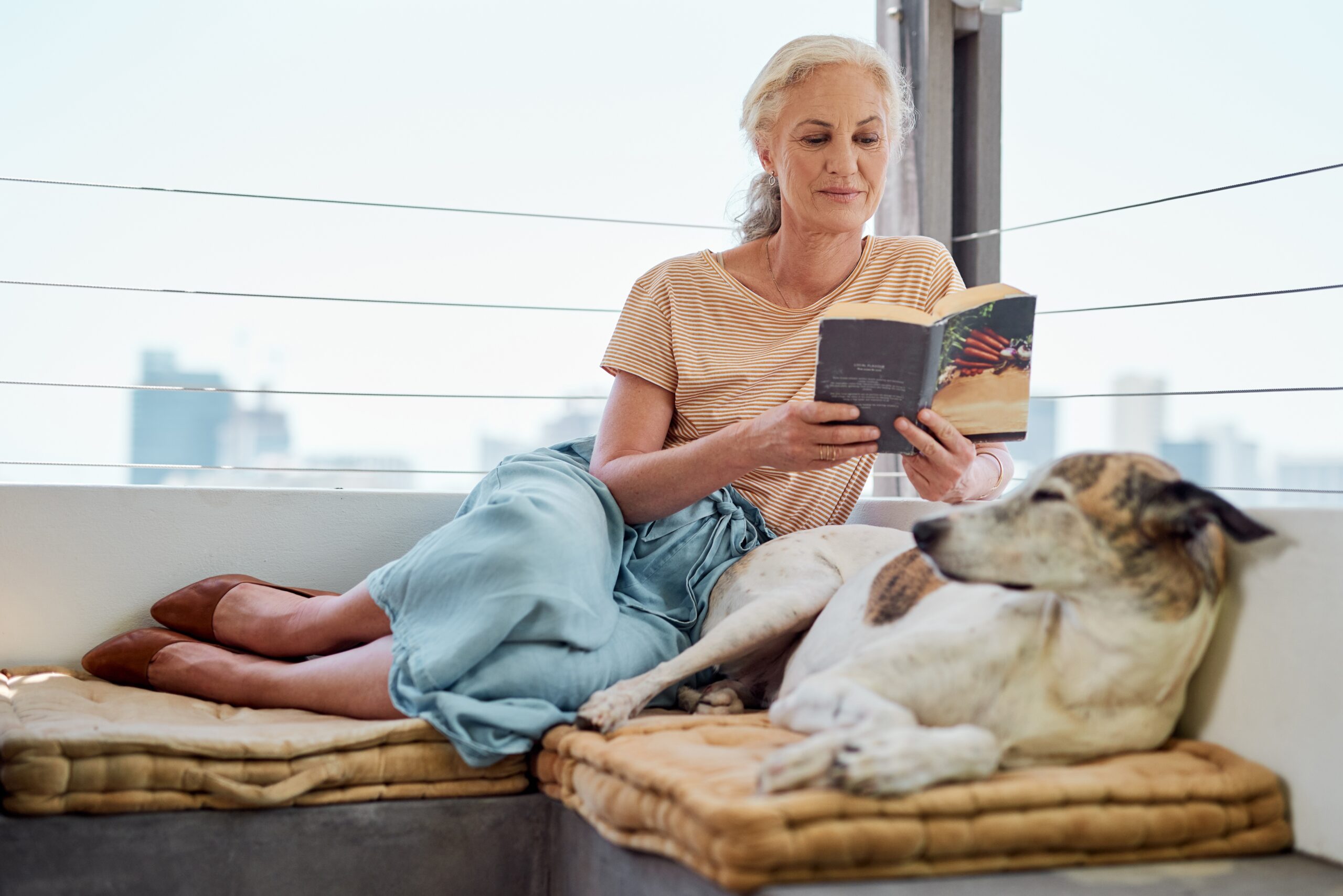 A woman spending time alone while reading with her dog.