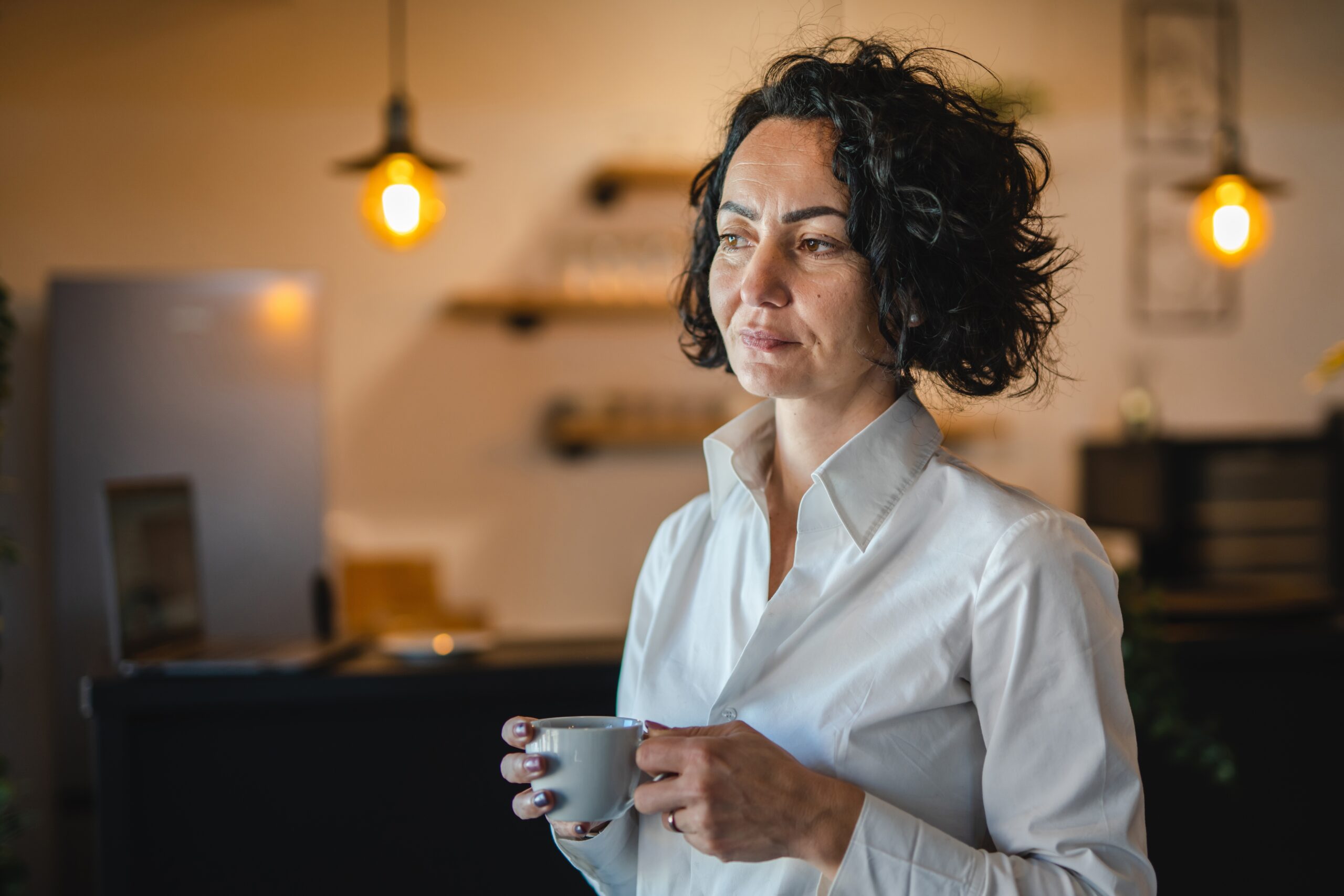 Woman standing alone having coffee thinking about her life.