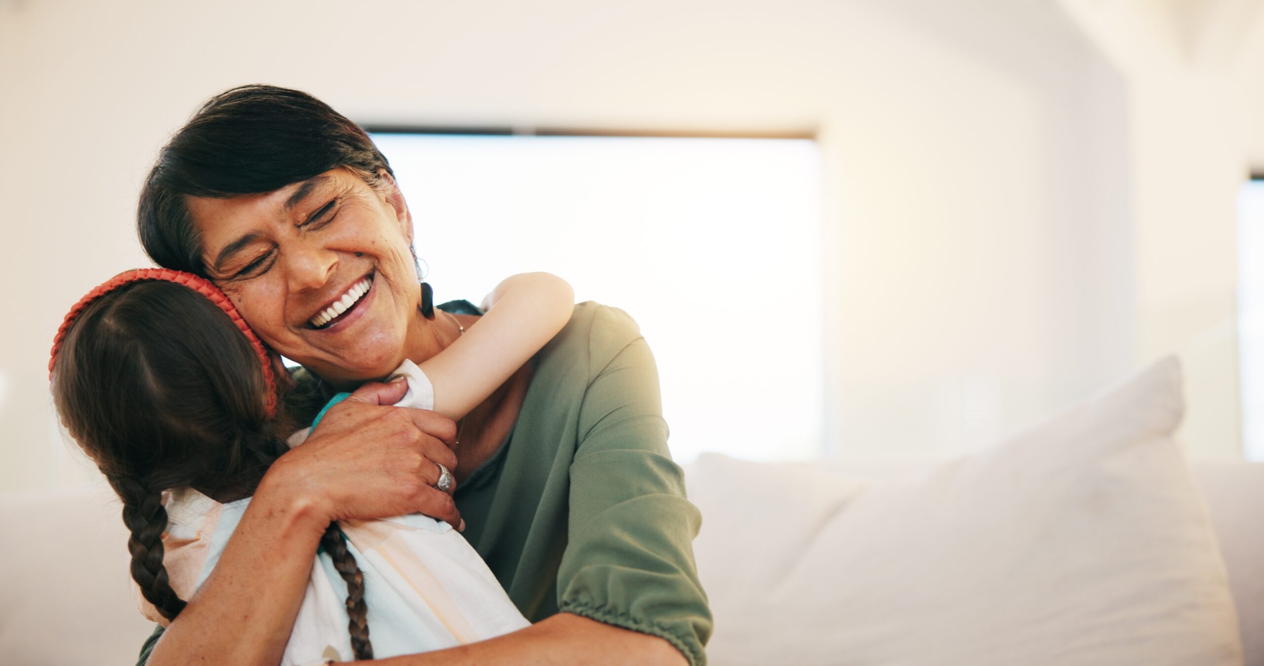 A grandmother hugging her grandchild at home.