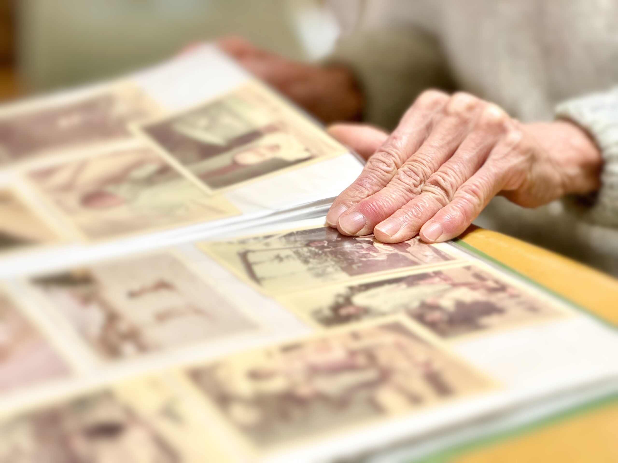The hand of an elderly woman looking at a photo album.