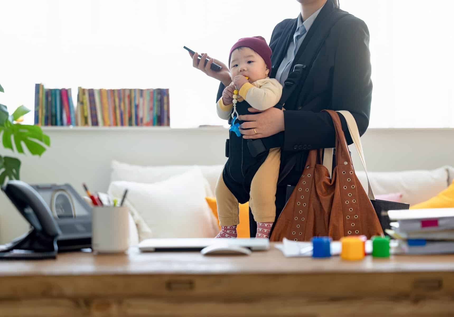 A working mother leaving home to go to the office carrying her baby.
