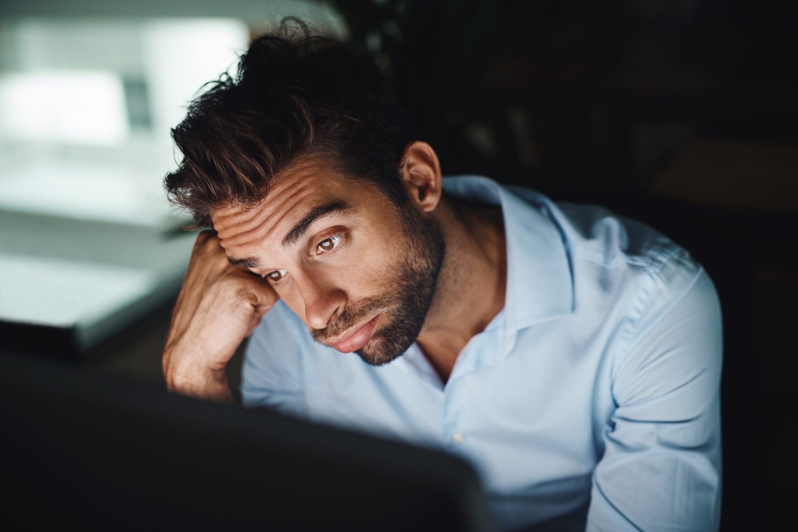 A man stuck in boredom looking at his computer screen.