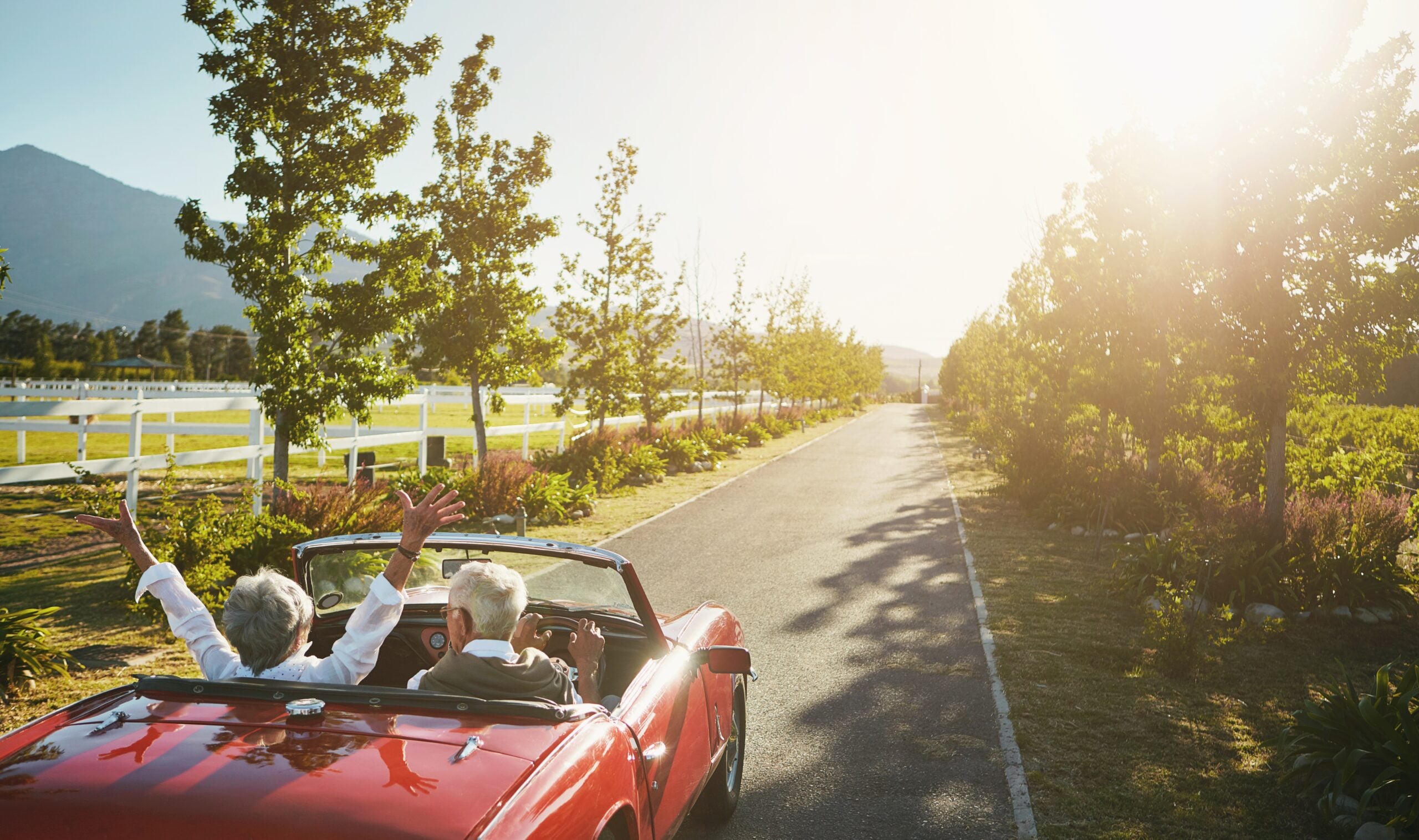 A senior couple in a convertible on a road trip celebration.