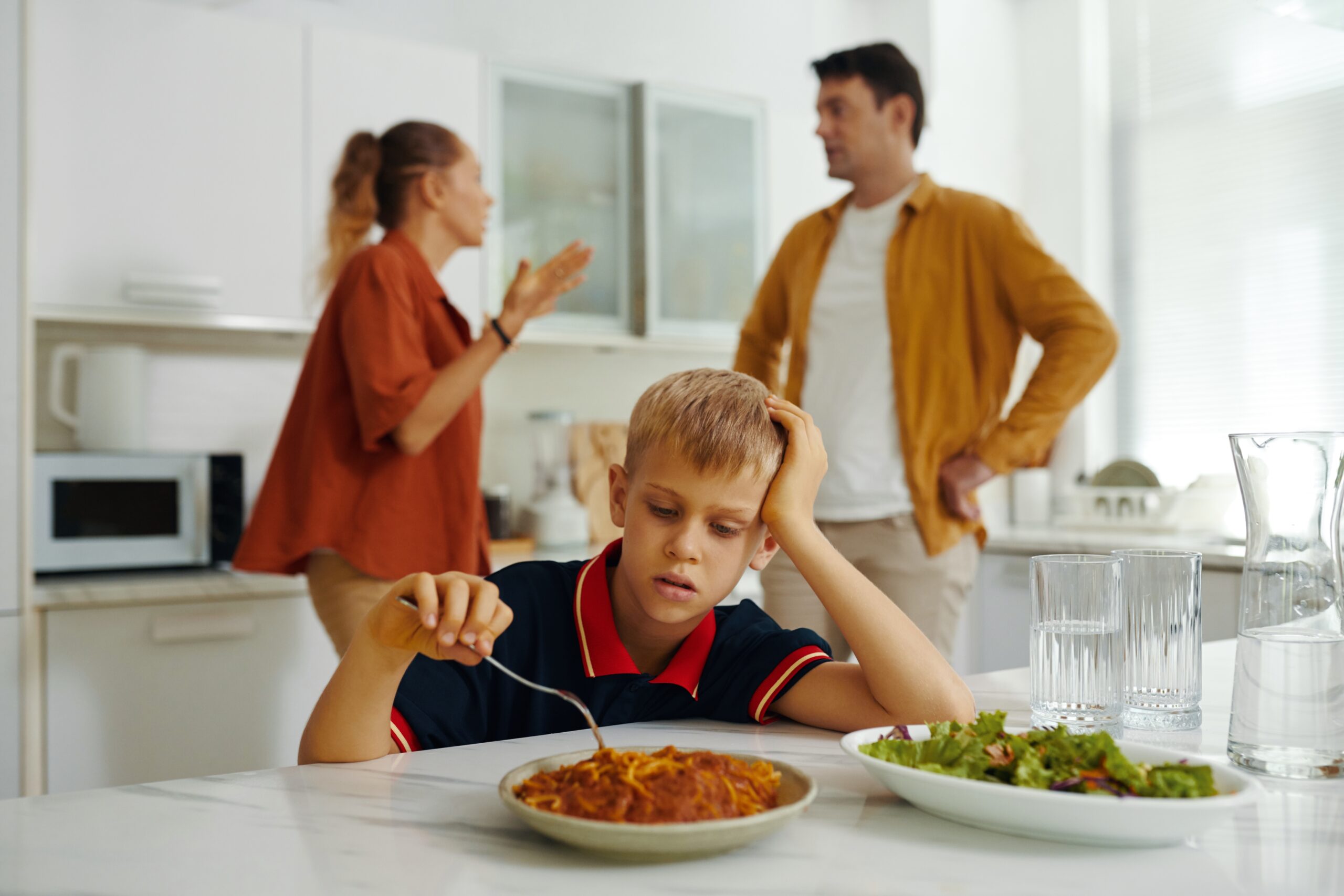 Child eating while parents argue in the background.