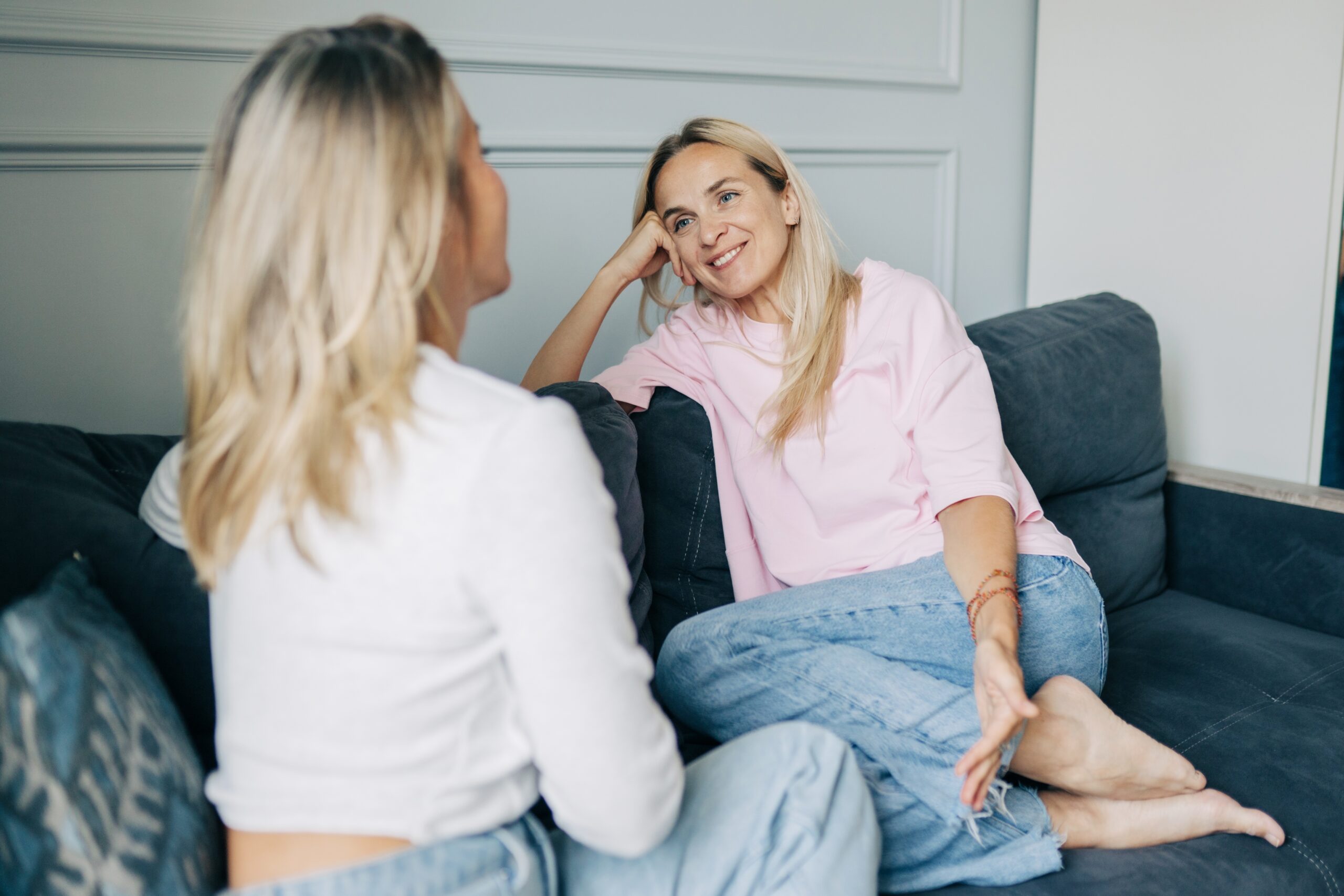 Two female friends chatting on the sofa together.