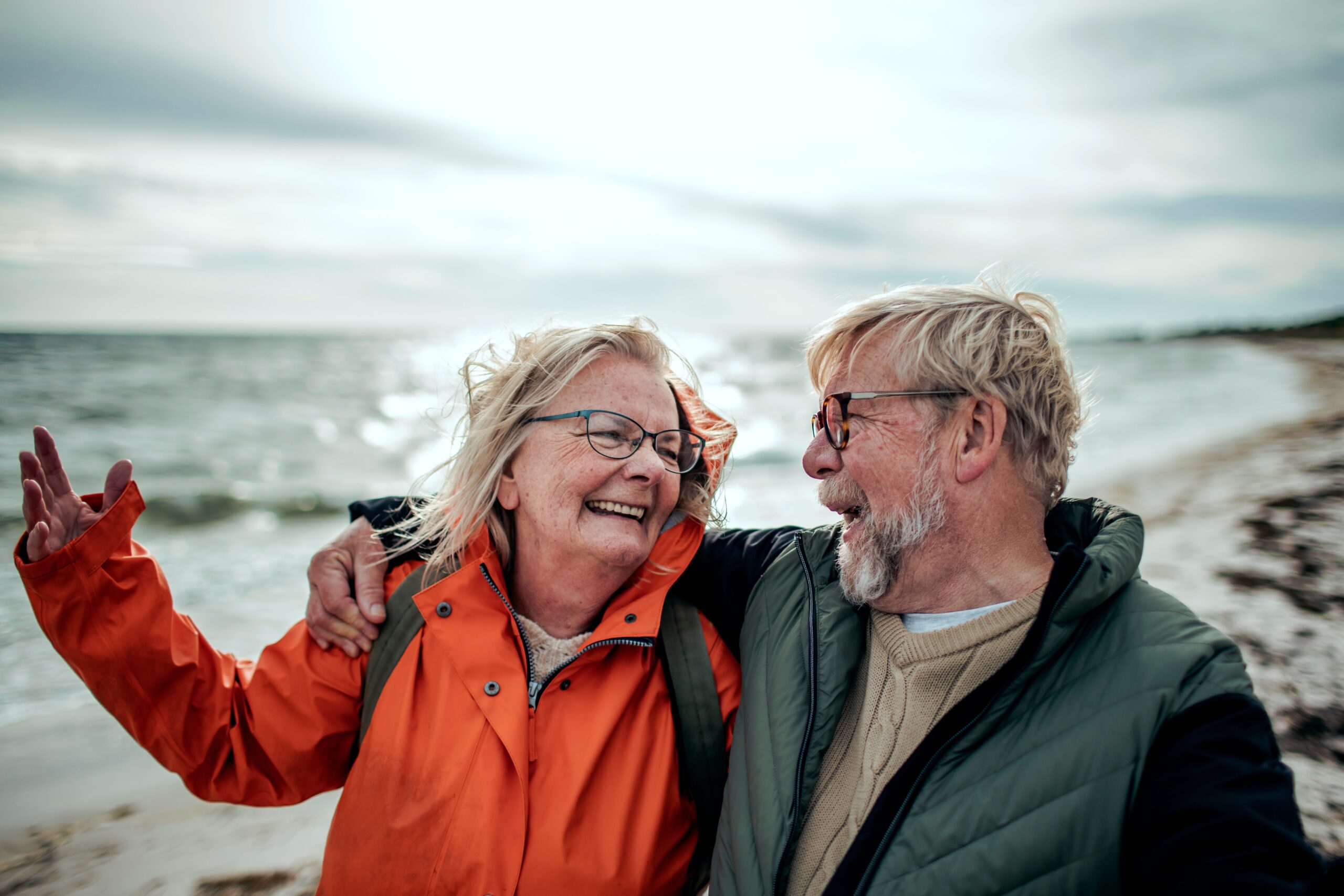 Happy senior couple walking on beach during winter.