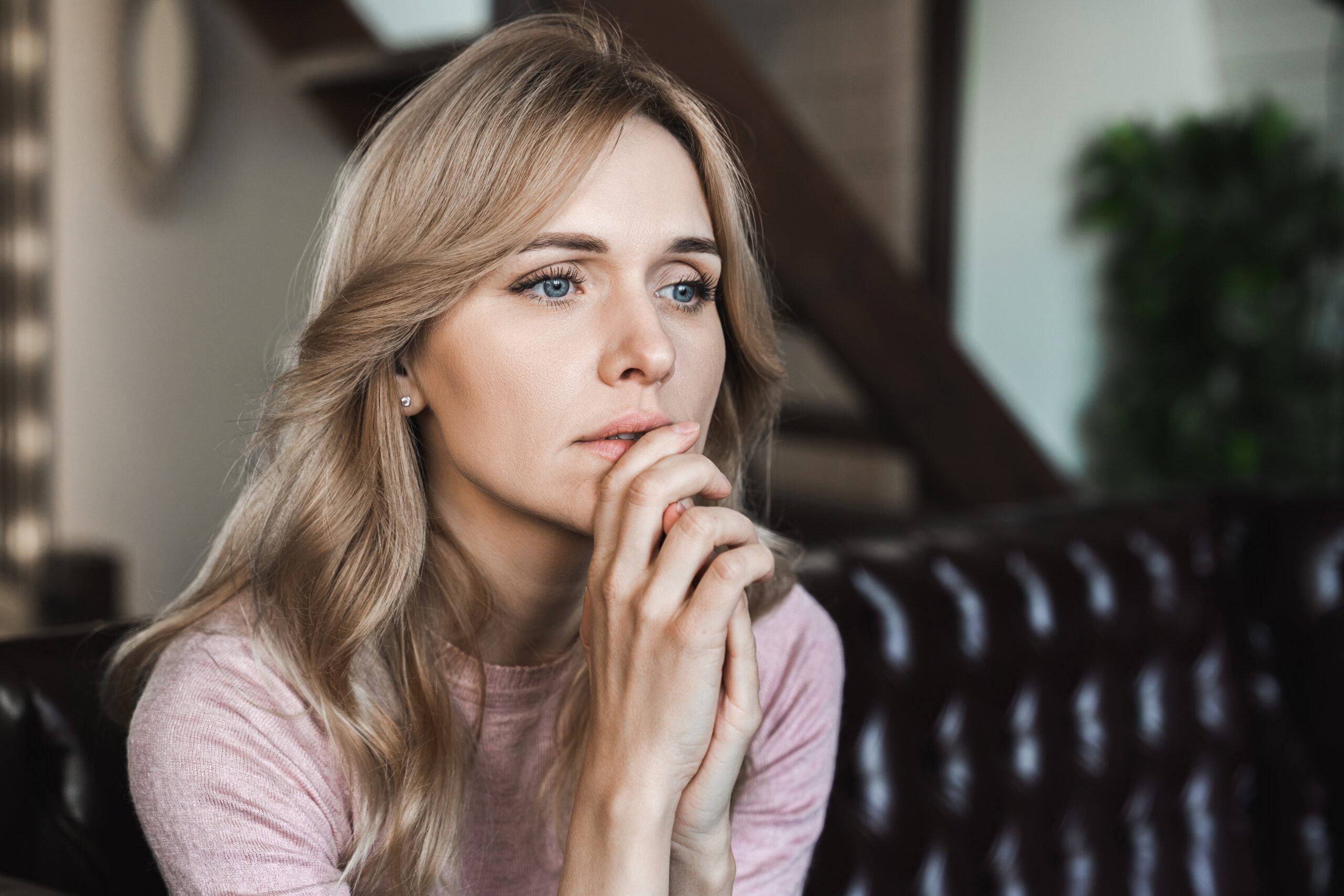 Woman sitting on couch looking pensive and sad.