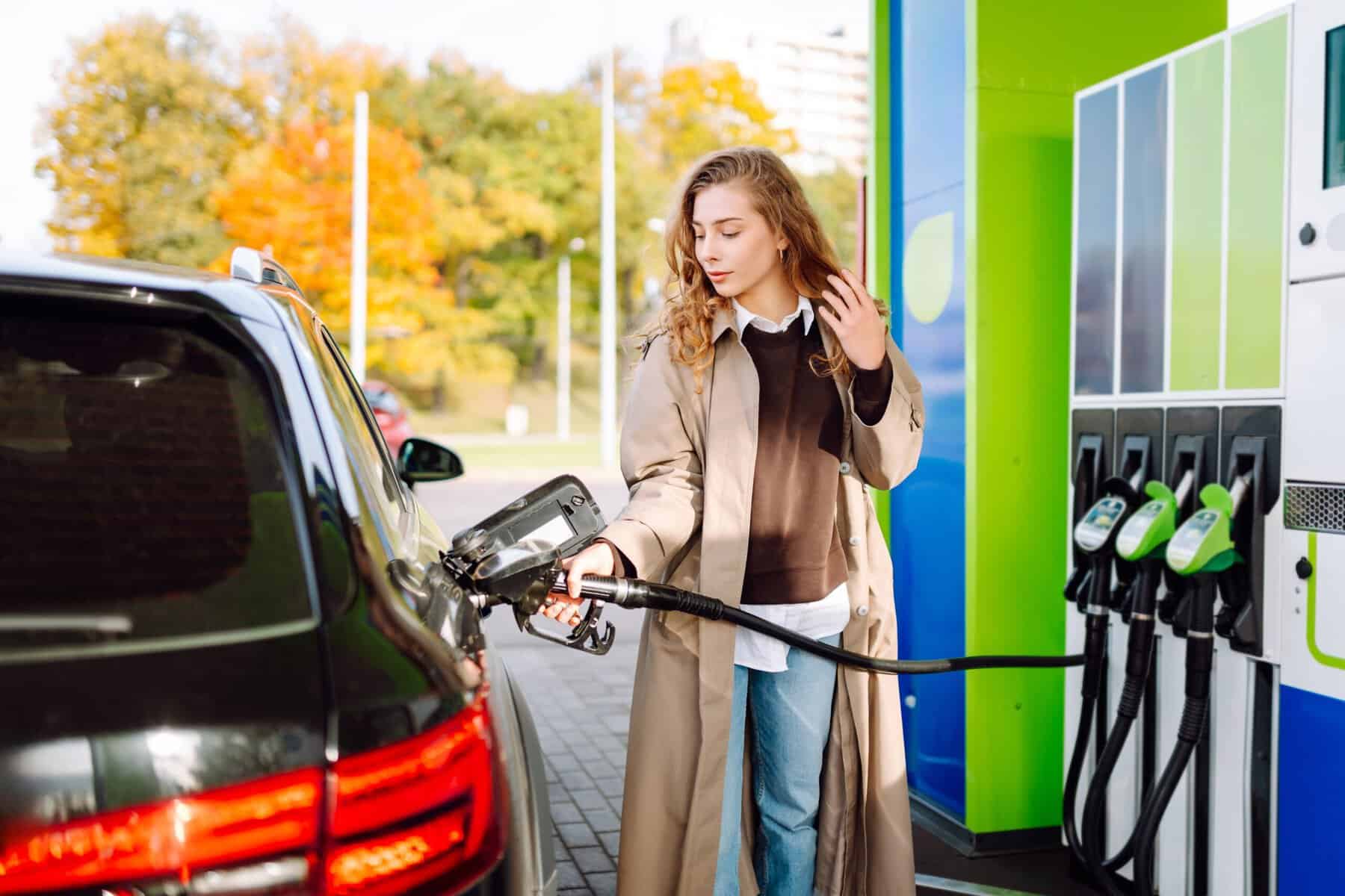 A woman filling her car up with gas at the station.