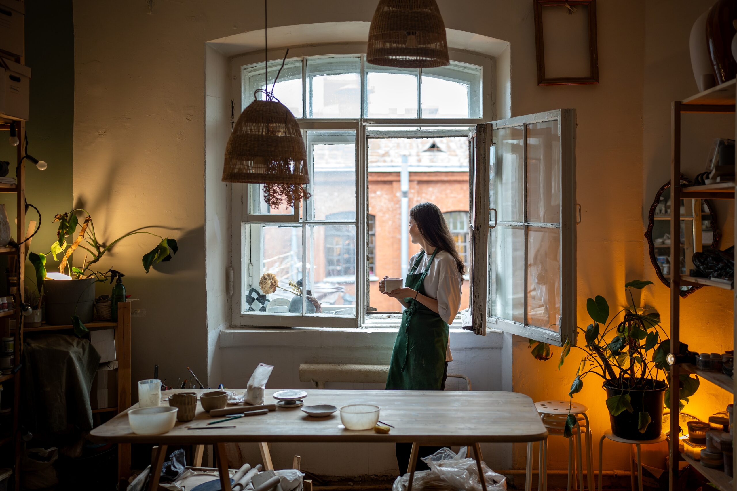 A woman standing alone in her studio window.
