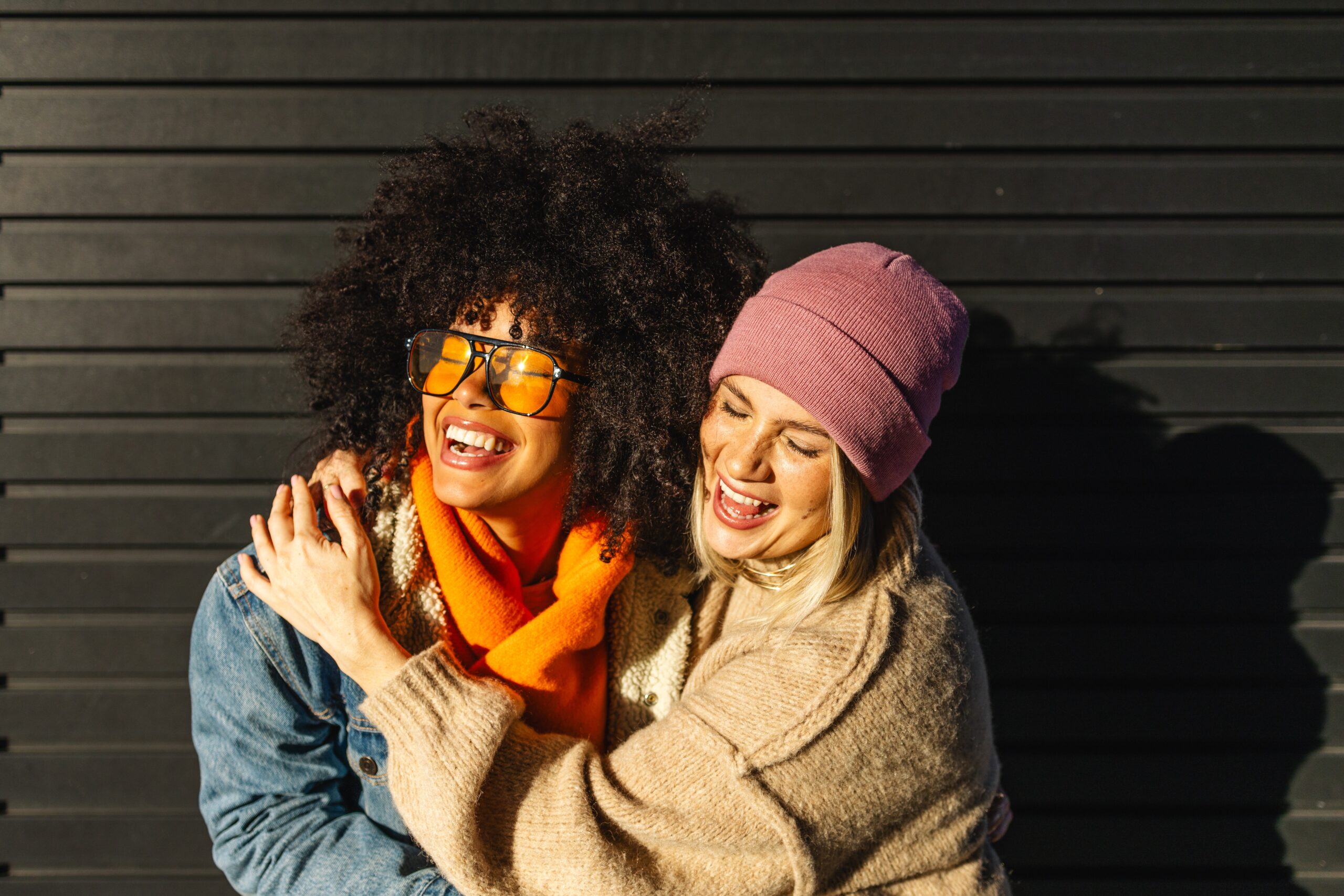 Two friends hugging and laughing while on a walk.