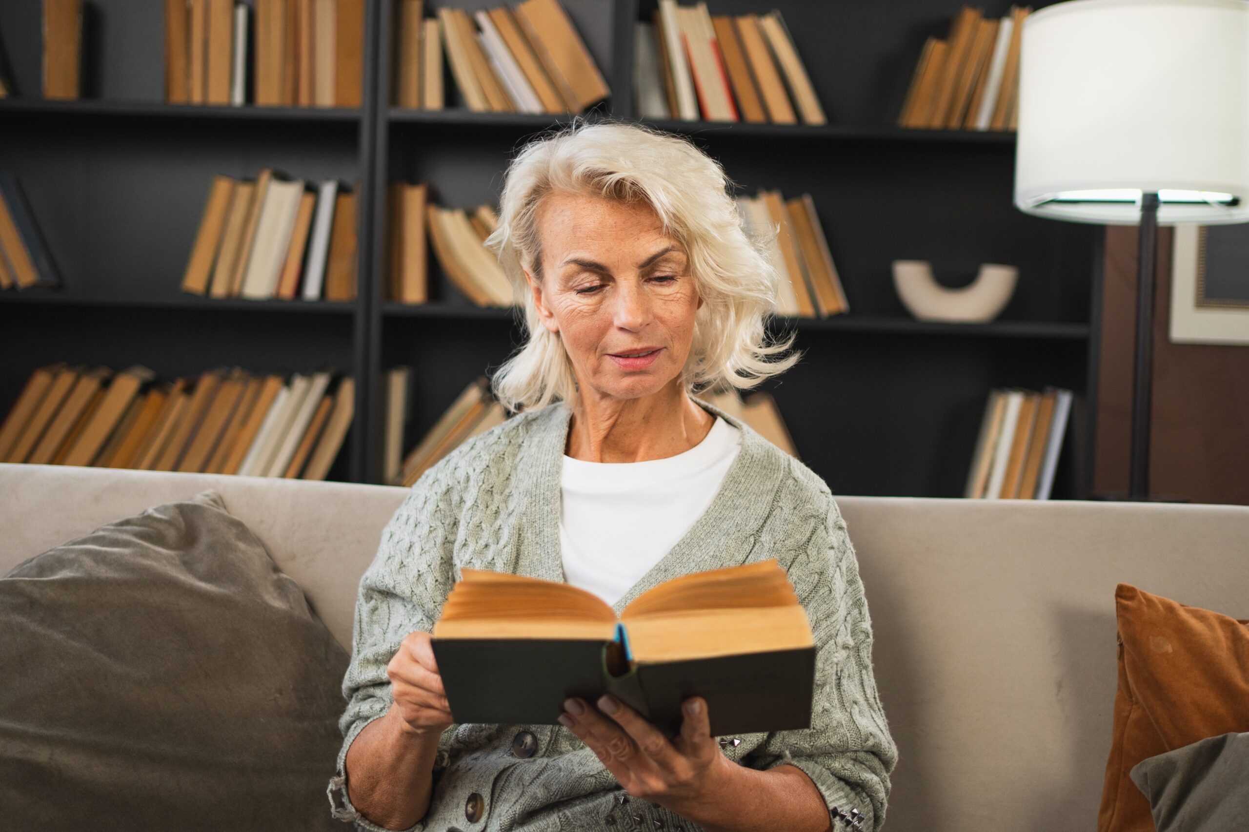 A relaxed mature woman reading a book at home.