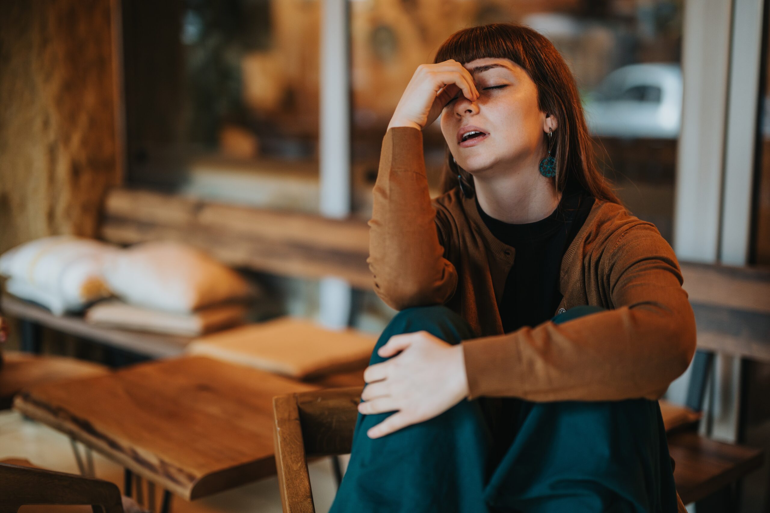 A visibly stressed woman sitting at a cafe.