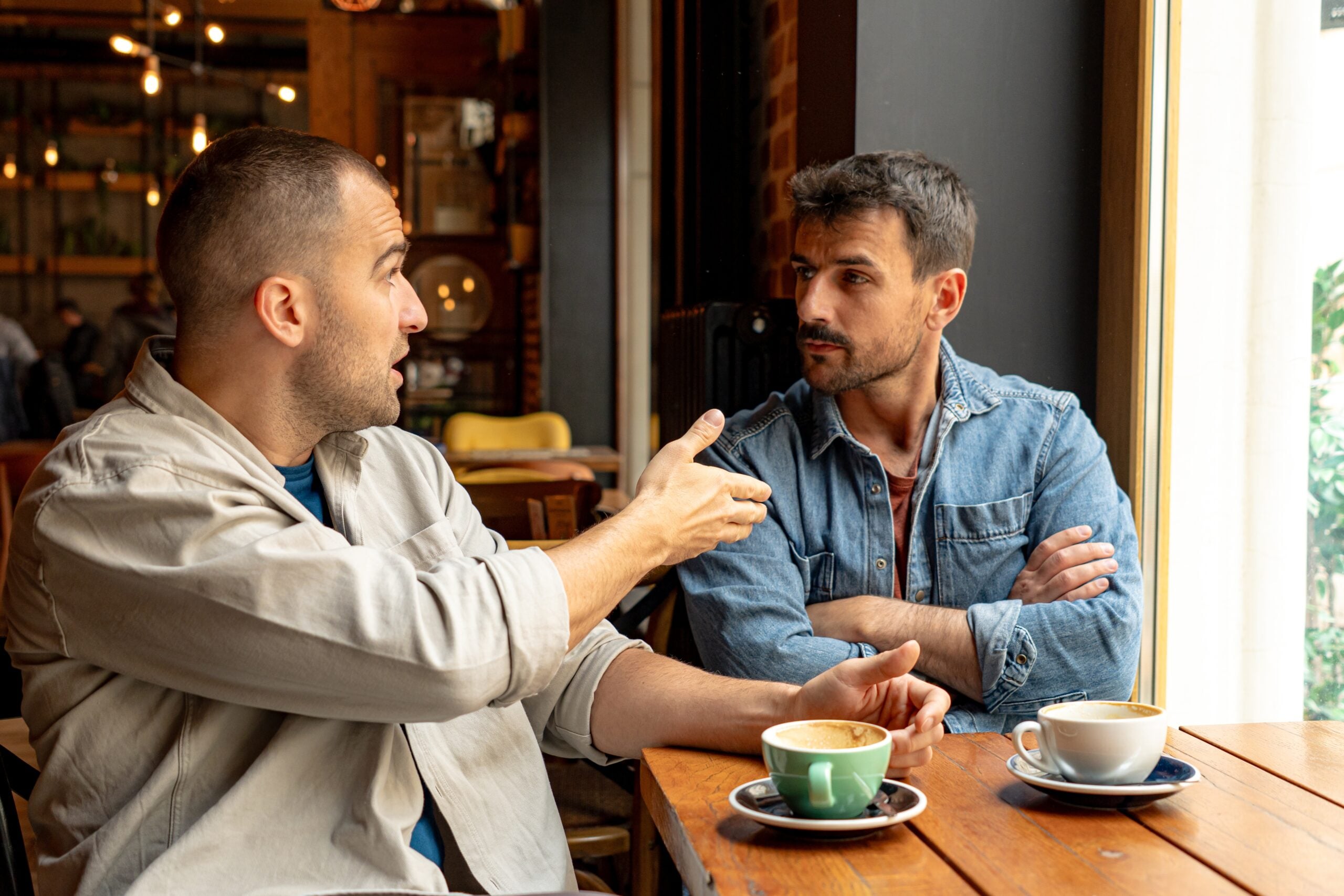 Two men having a serious discussion while drinking coffee in a cafe.
