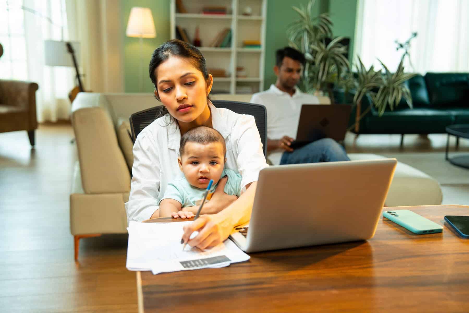 A multitasking mother with her infant baby working from home.