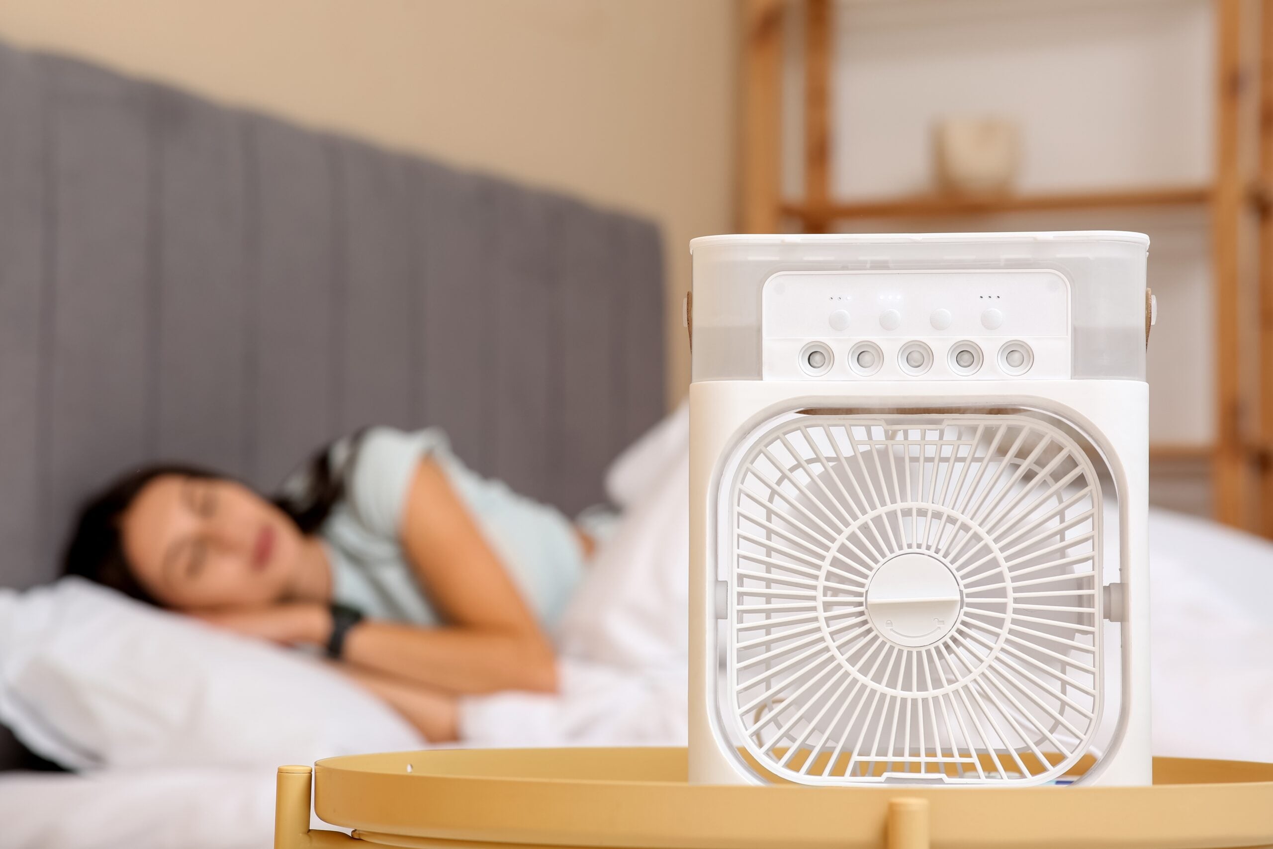 Woman sleeping with a fan in the bedroom.