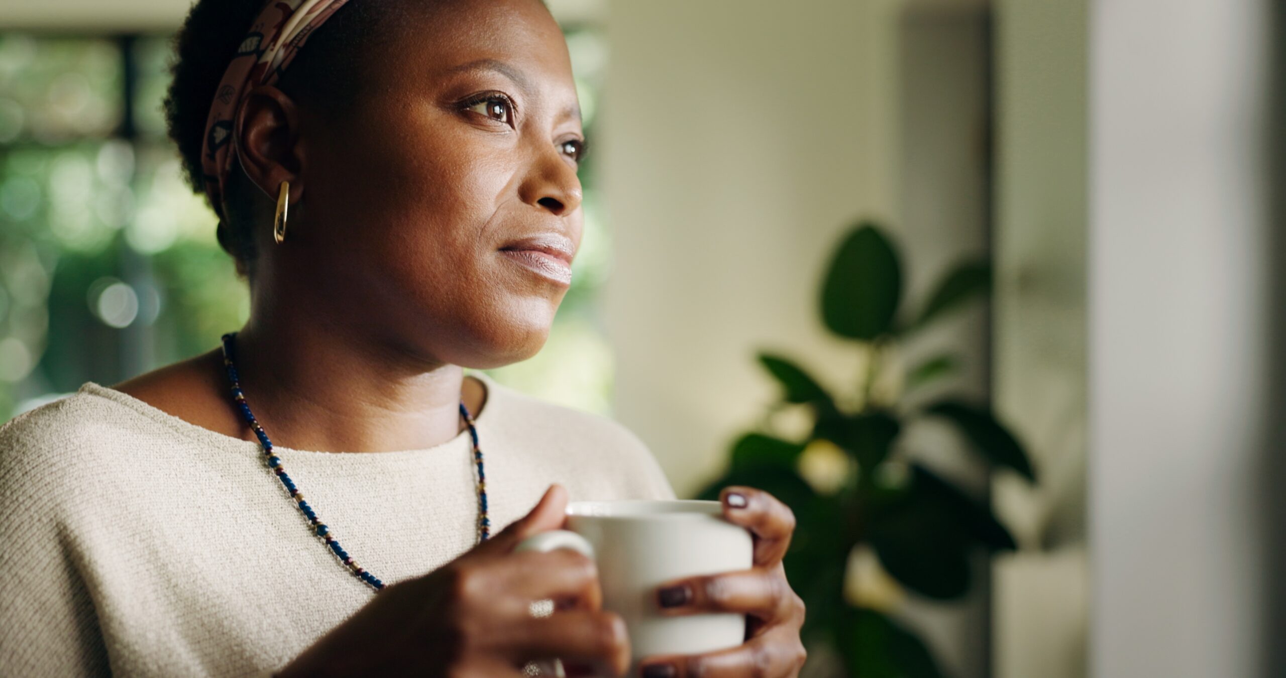 A middle aged woman sitting alone with a cup of tea.
