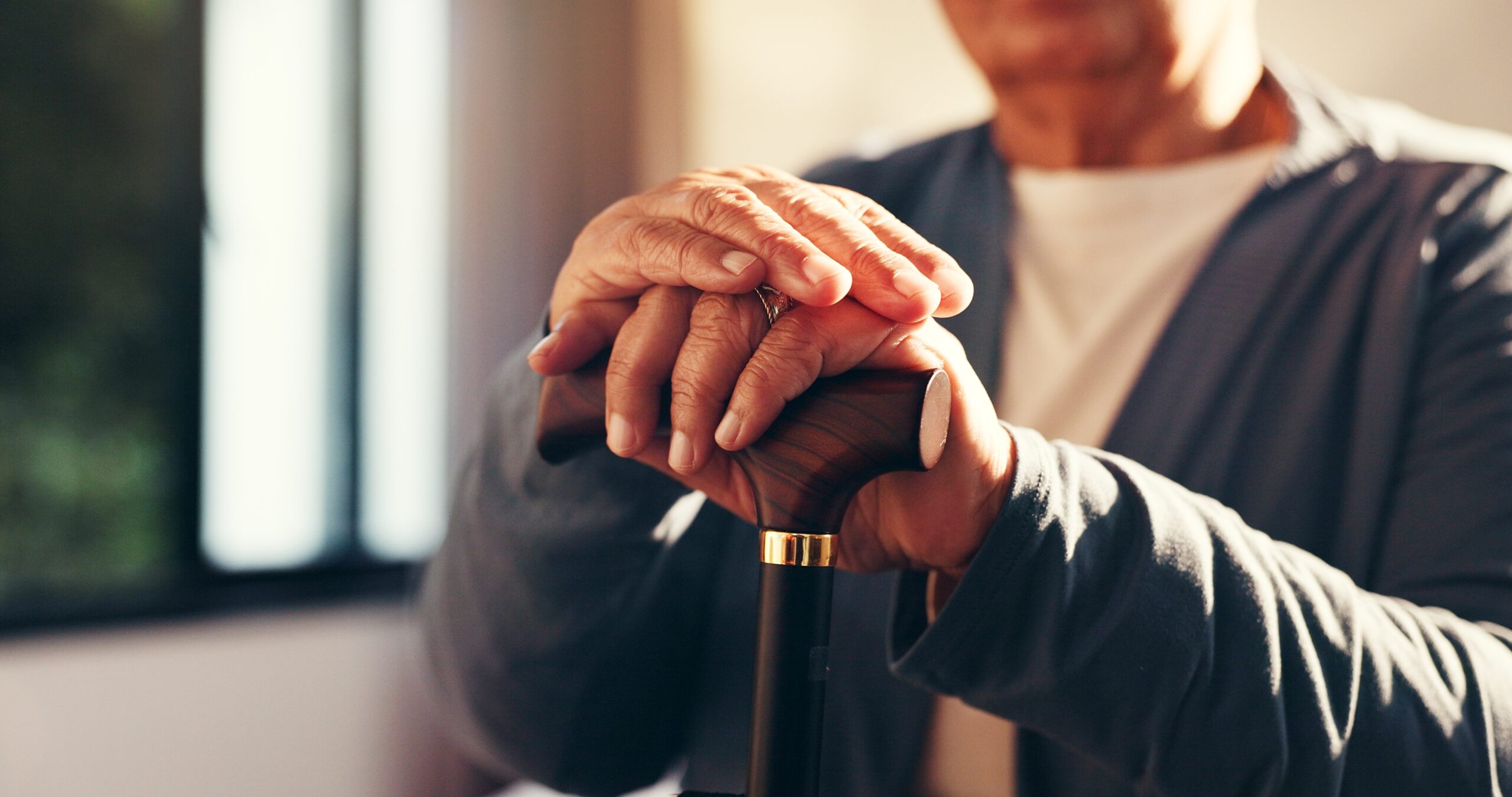 A senior man sitting alone with his walking stick.
