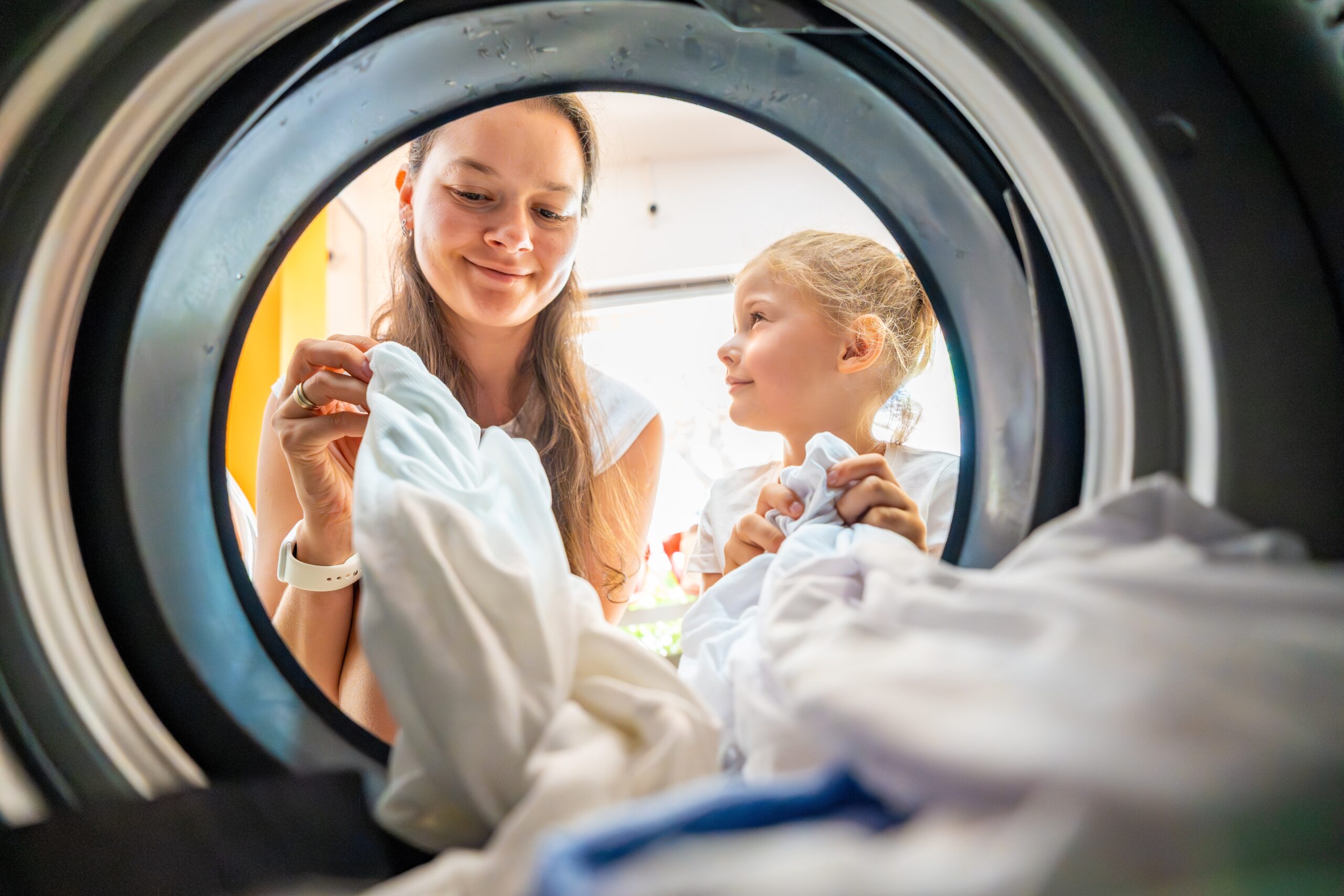 A mother doing laundry with her young daughter. 