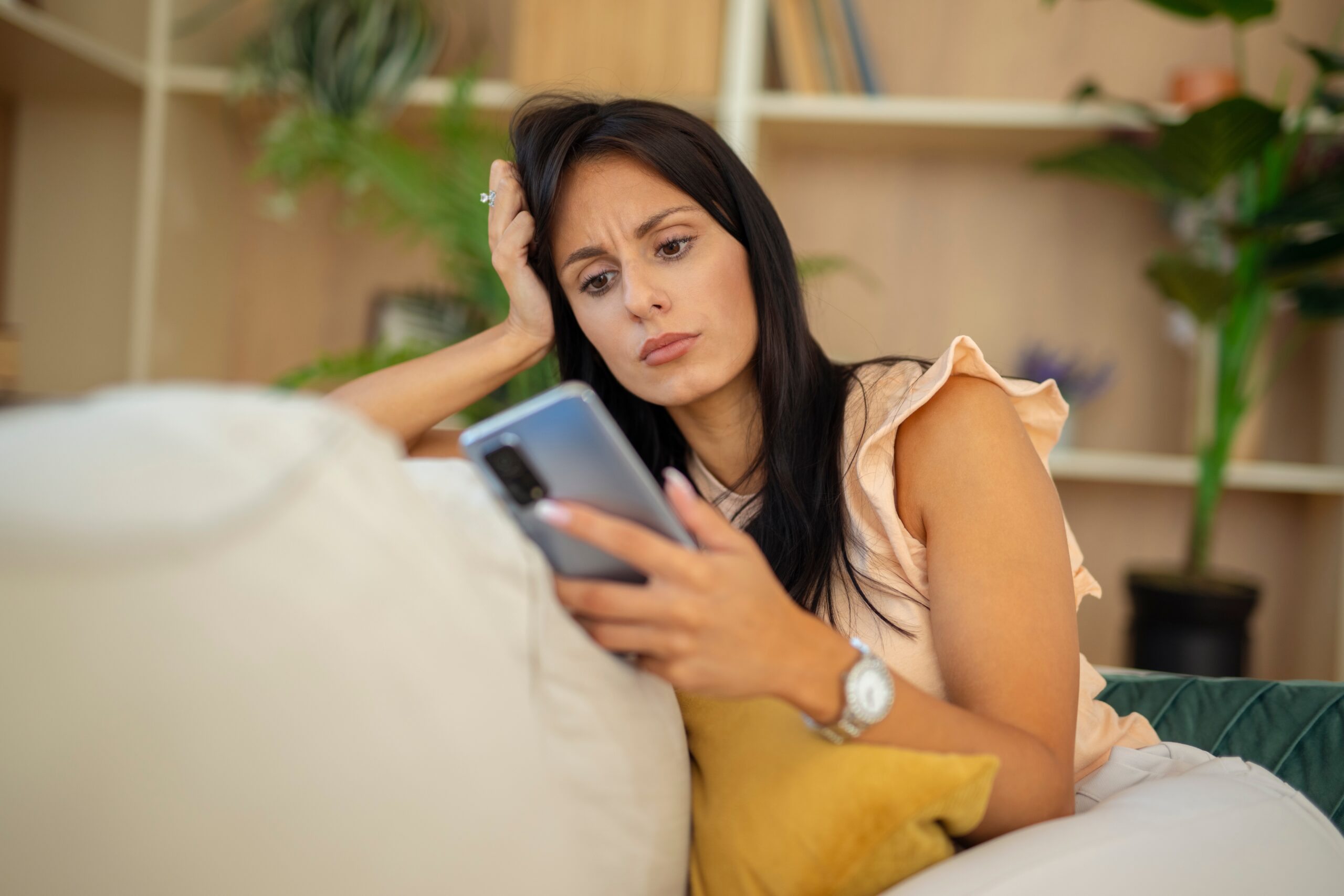 Lonely woman sitting on her couch waiting for a message.