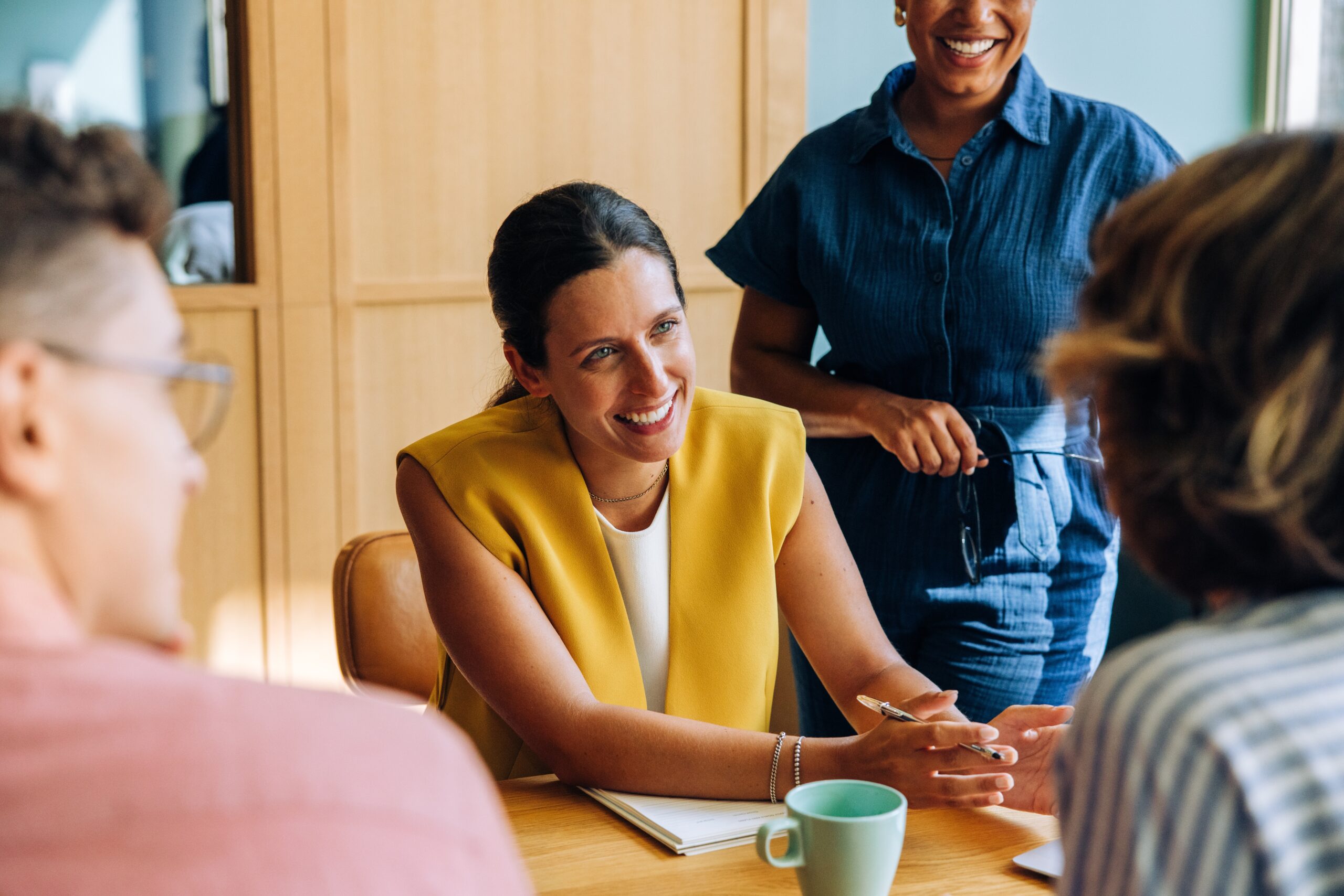 A professional woman leading a friendly discussion with colleagues during a meeting.
