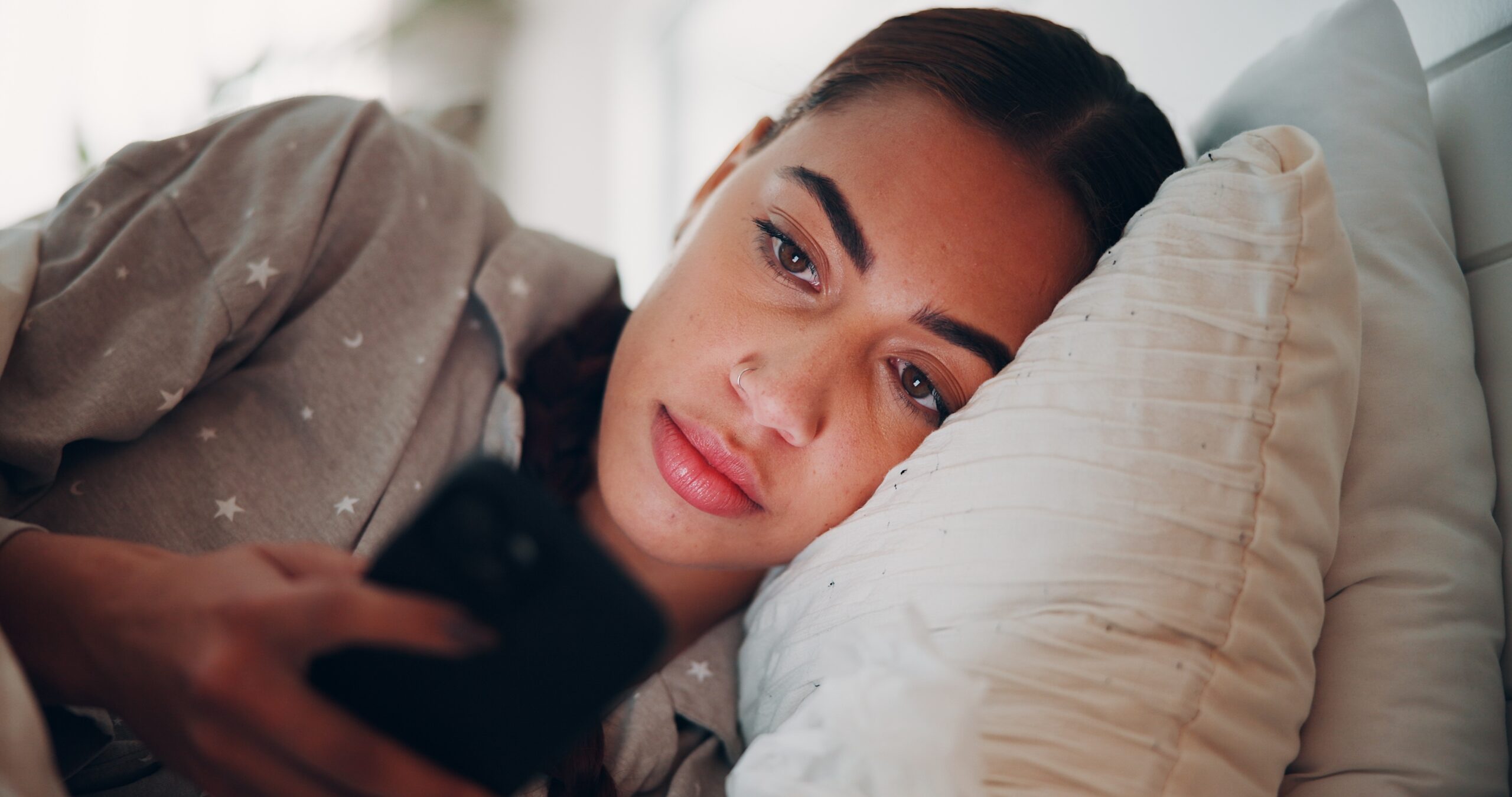 A woman at home reading texts while in bed.