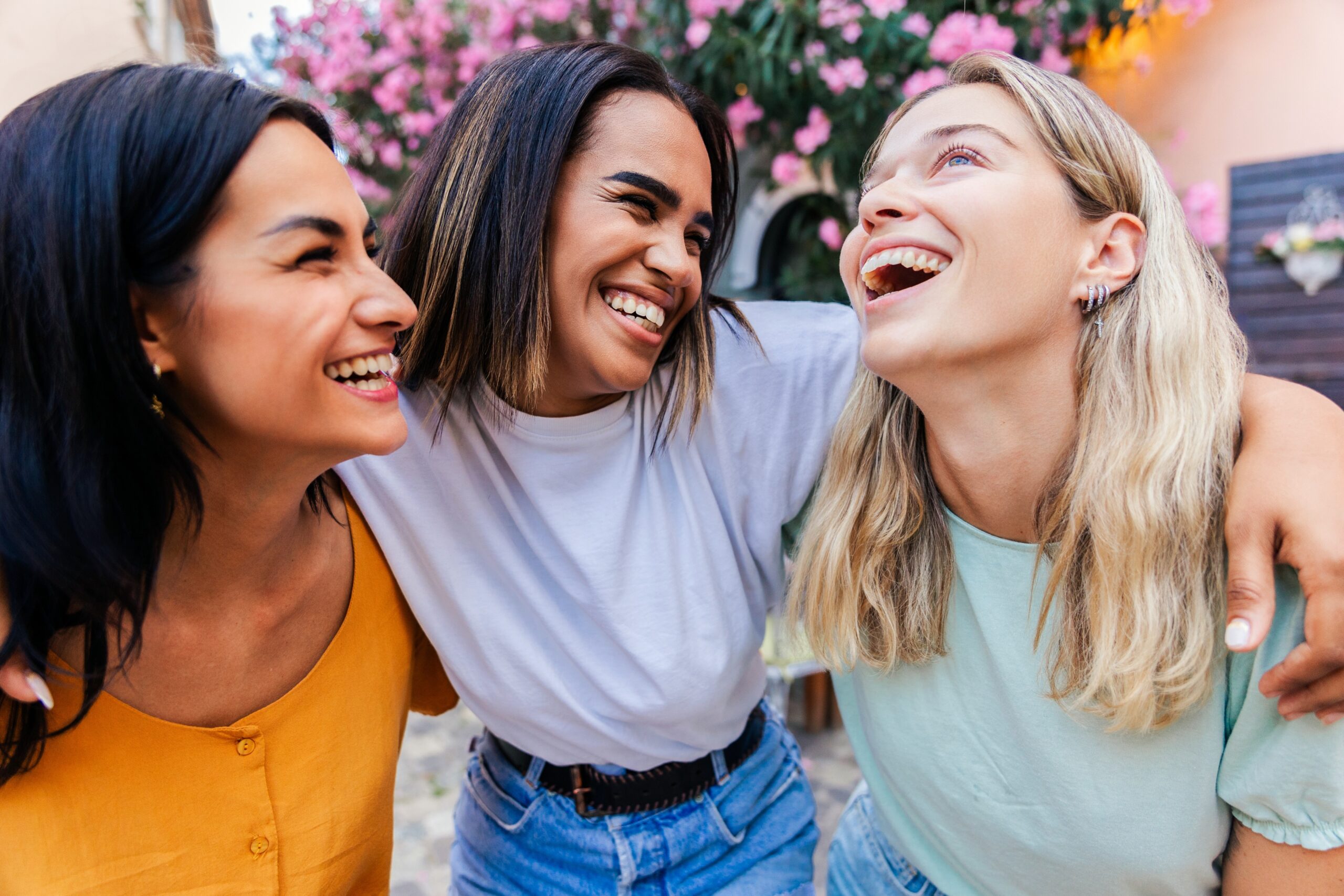 Three close female friends laughing with one another.