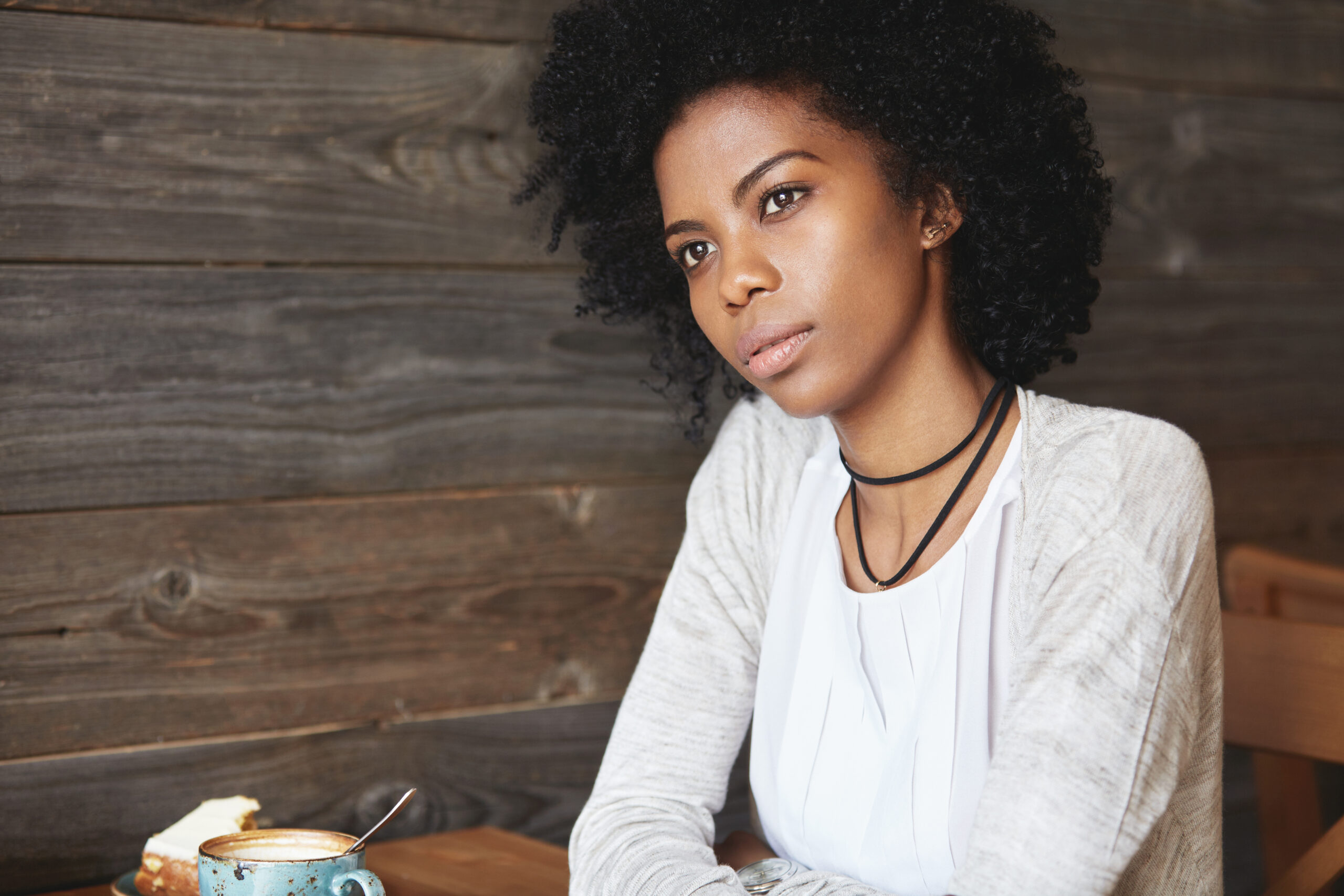 A woman sitting alone waiting for her friend at a coffee shop.