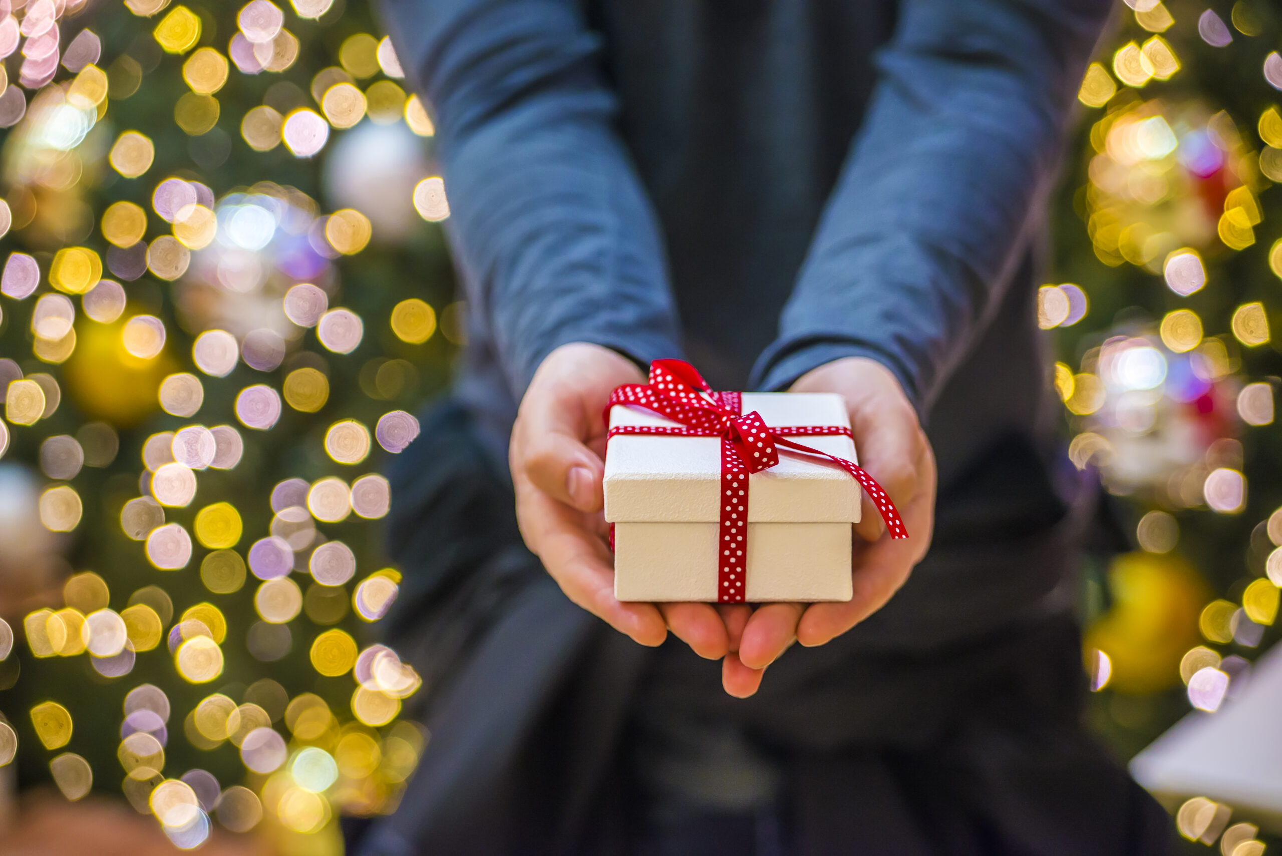 Man holding a gift box toward someone.