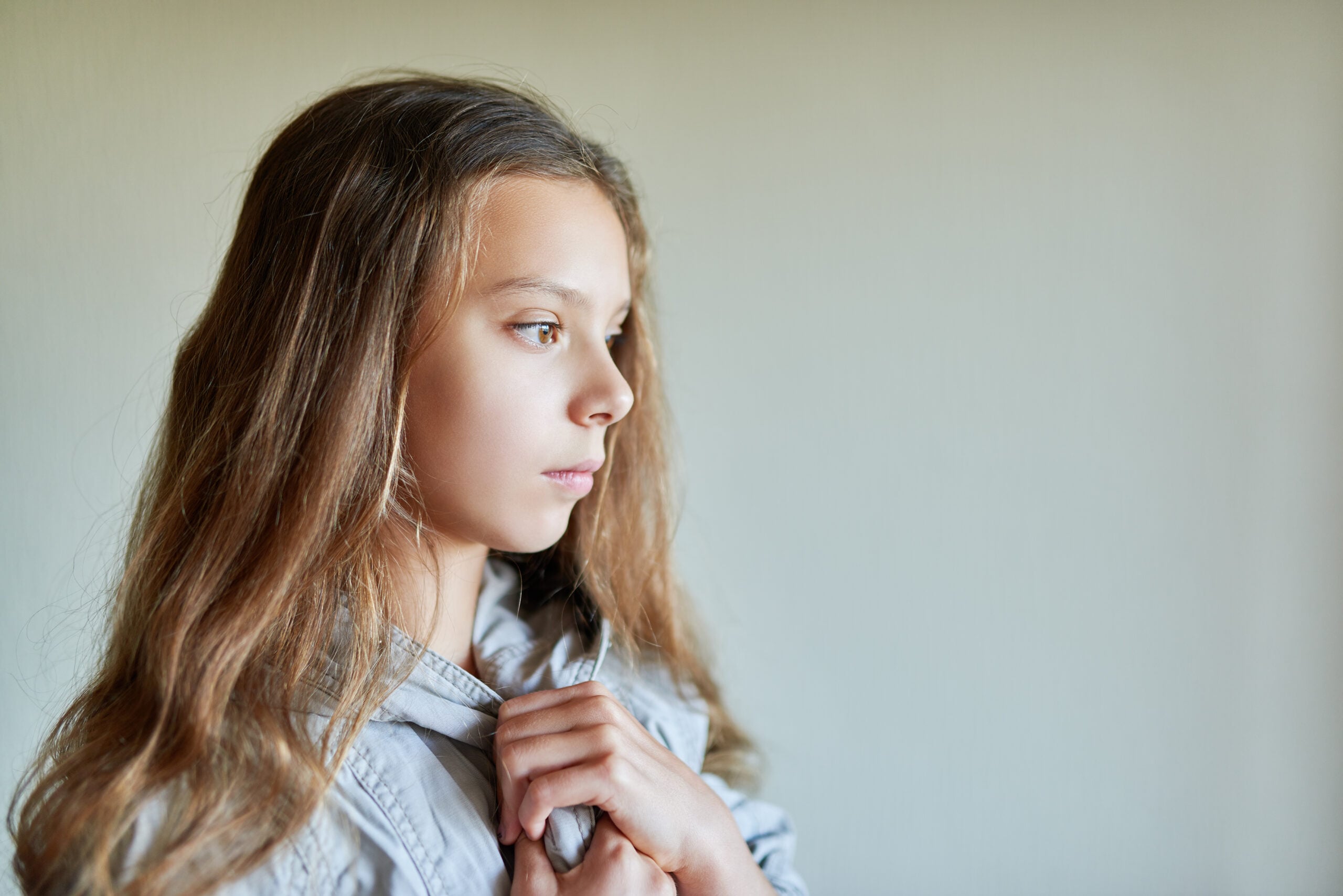 A young child standing alone deep in thought.