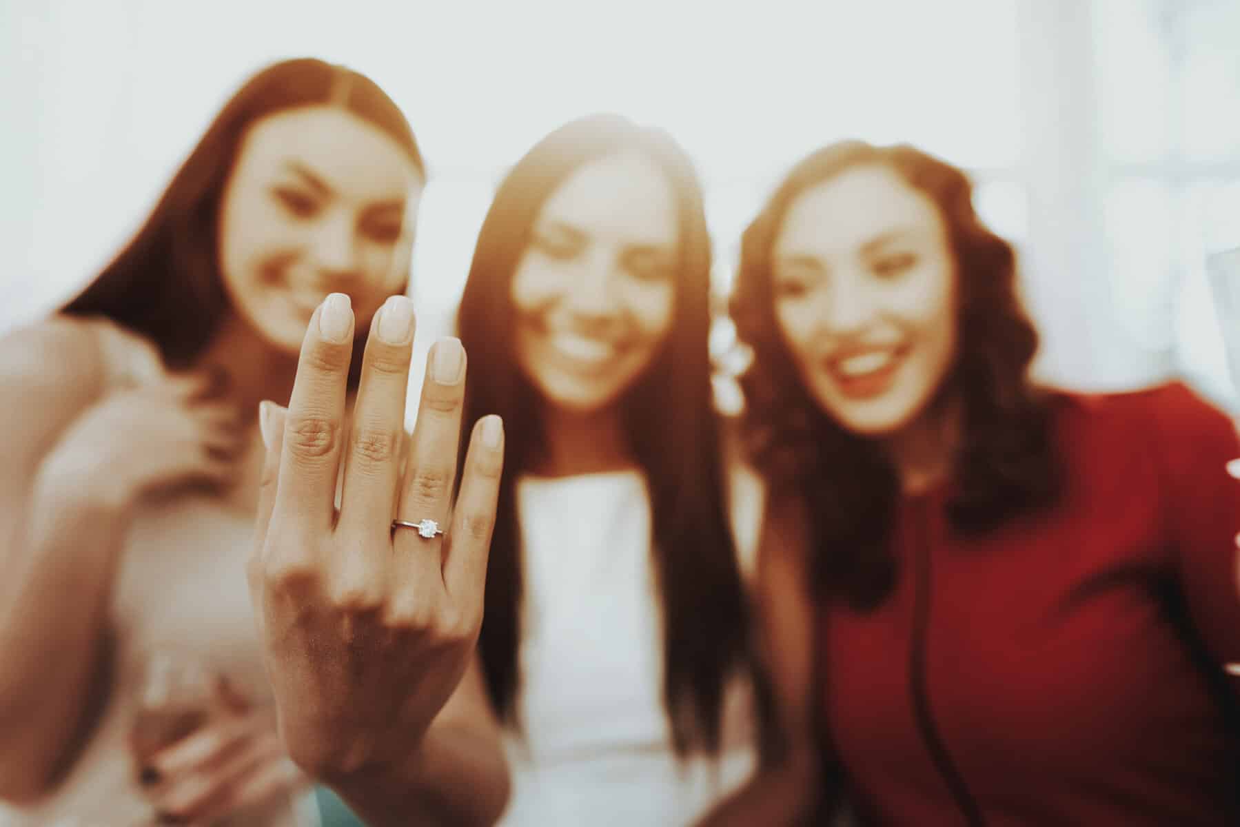 A woman showing her engagement ring to her friends.