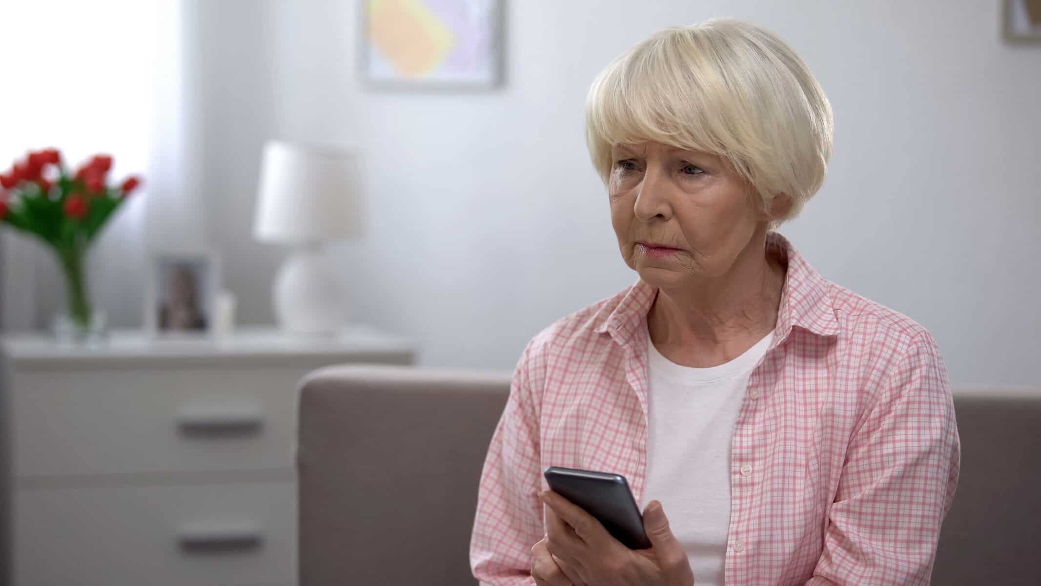 Lonely mother in her 60s watching her phone, waiting for her daughter to call.