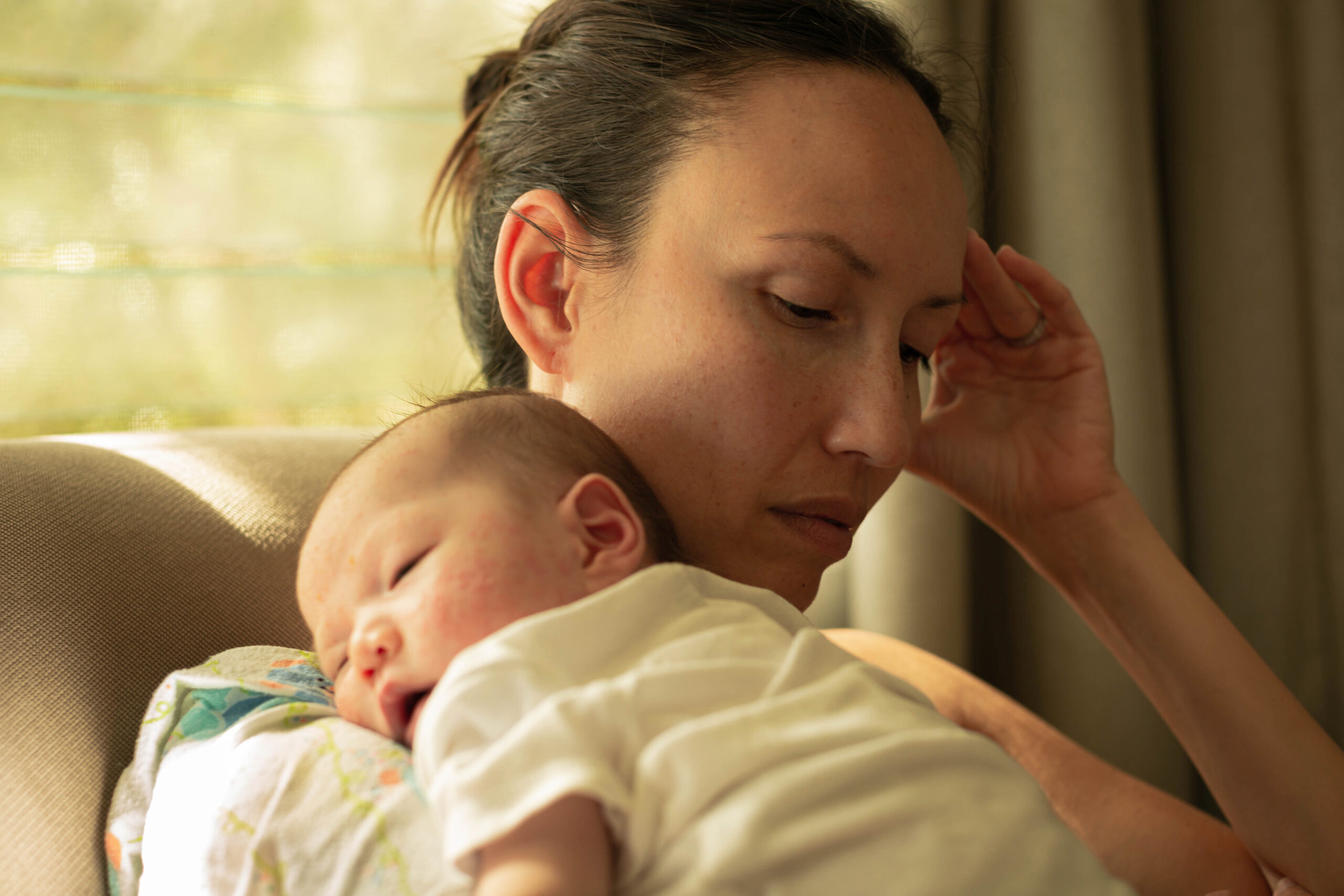 An exhausted new mother caring for her infant.