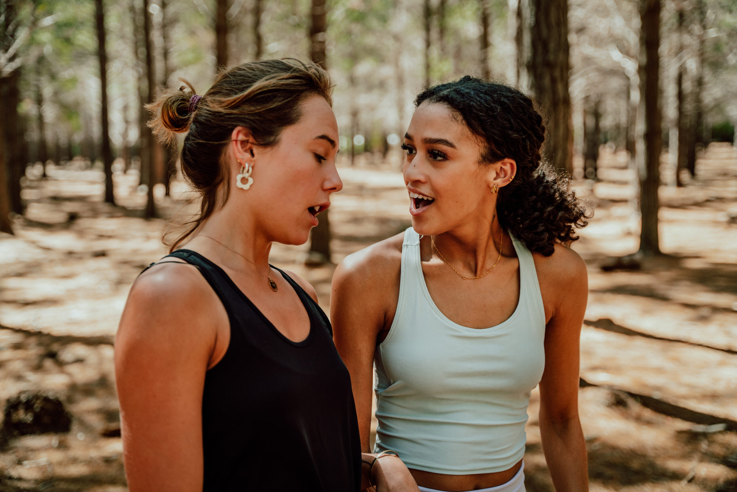 Two female friends chatting together while walking in nature.