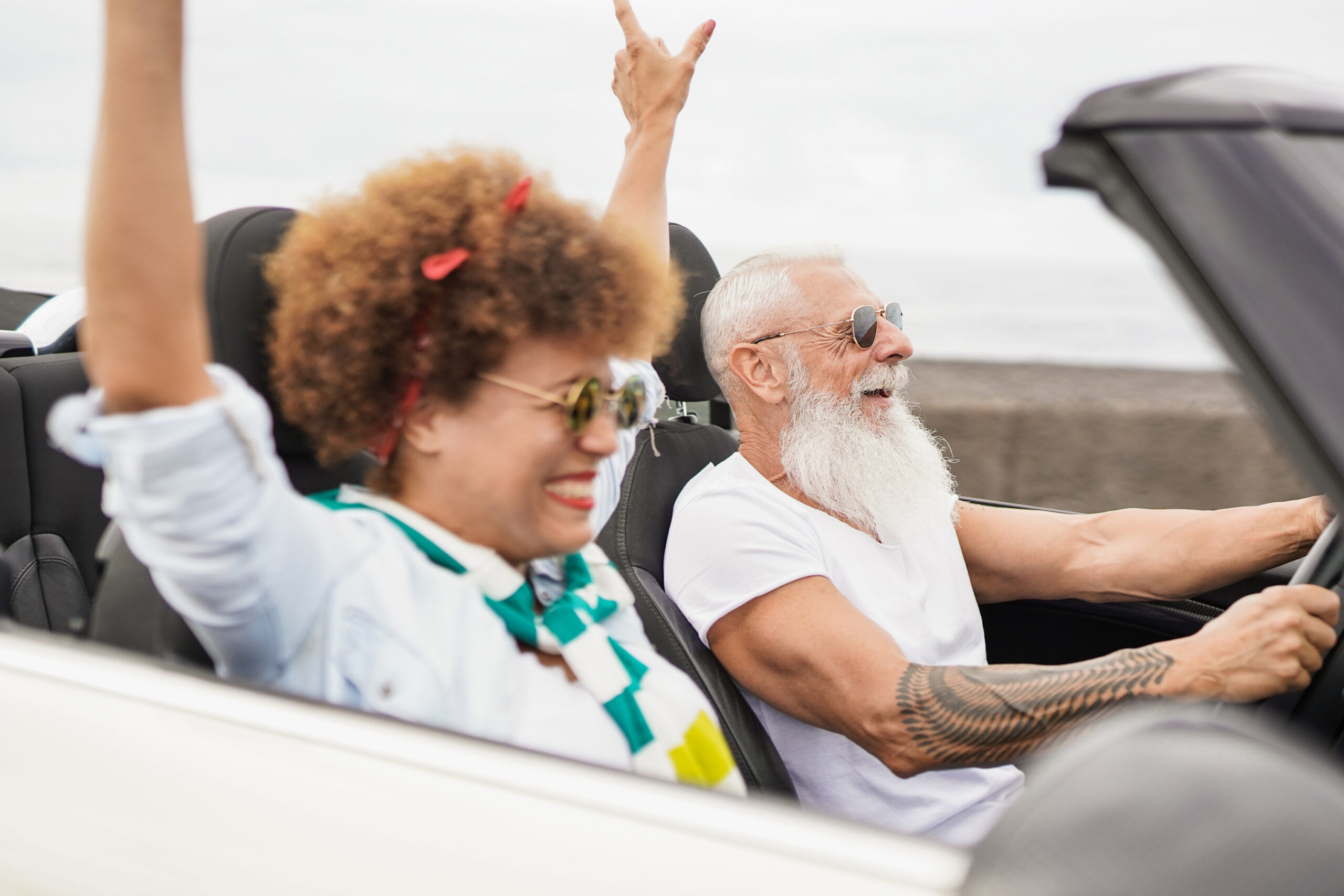 A senior couple having fun on a roadtrip in convertible their car.