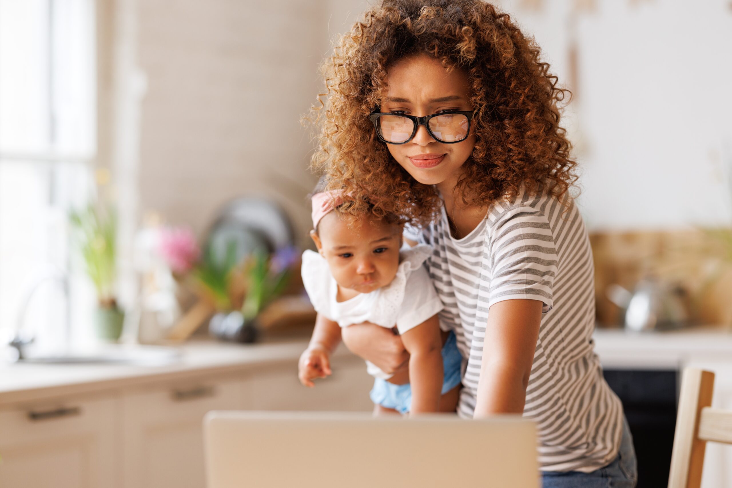 A multitasking mother at home with her infant.