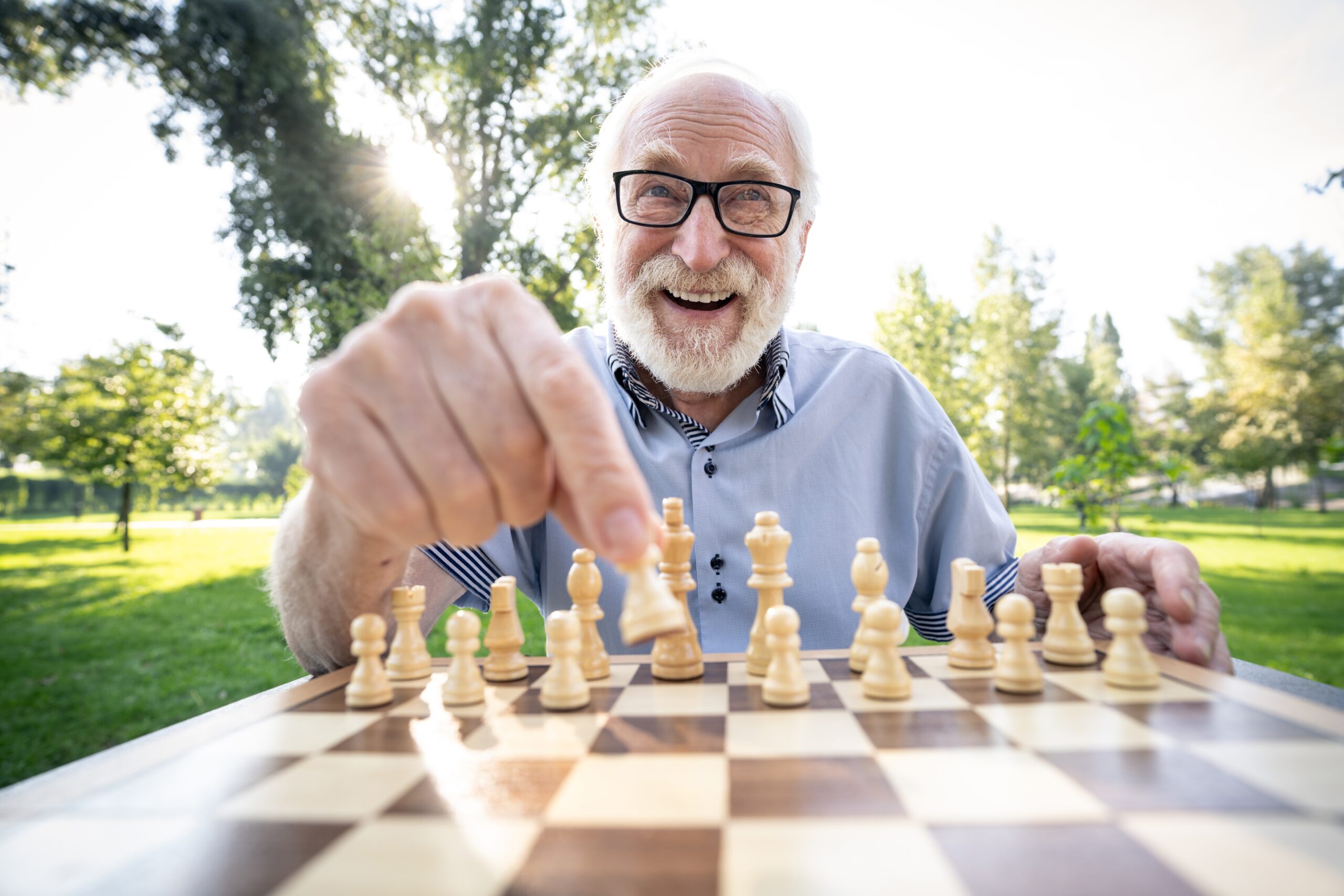 A group of senior friends playing chess at the park.