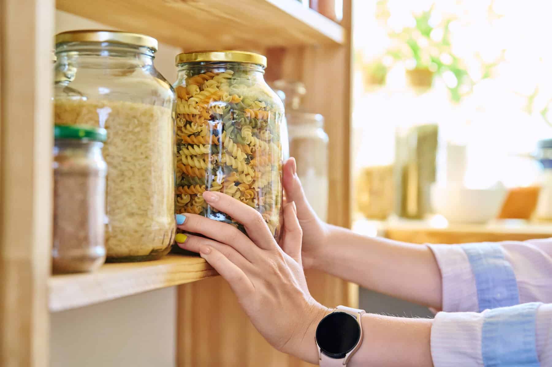 A woman stocking her pantry shelf with staples.