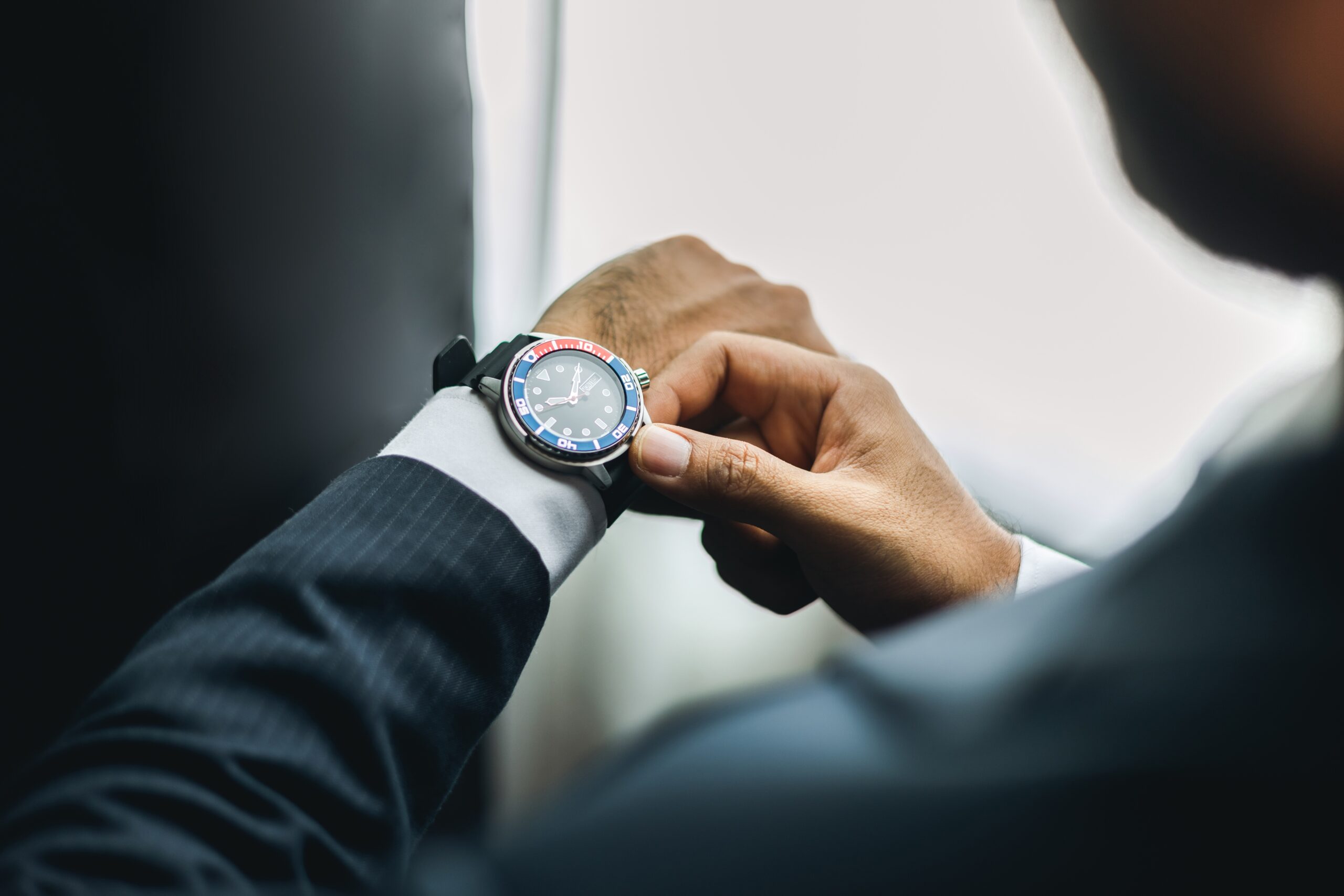 A successful businessman in a blue suit adjusting his watch.