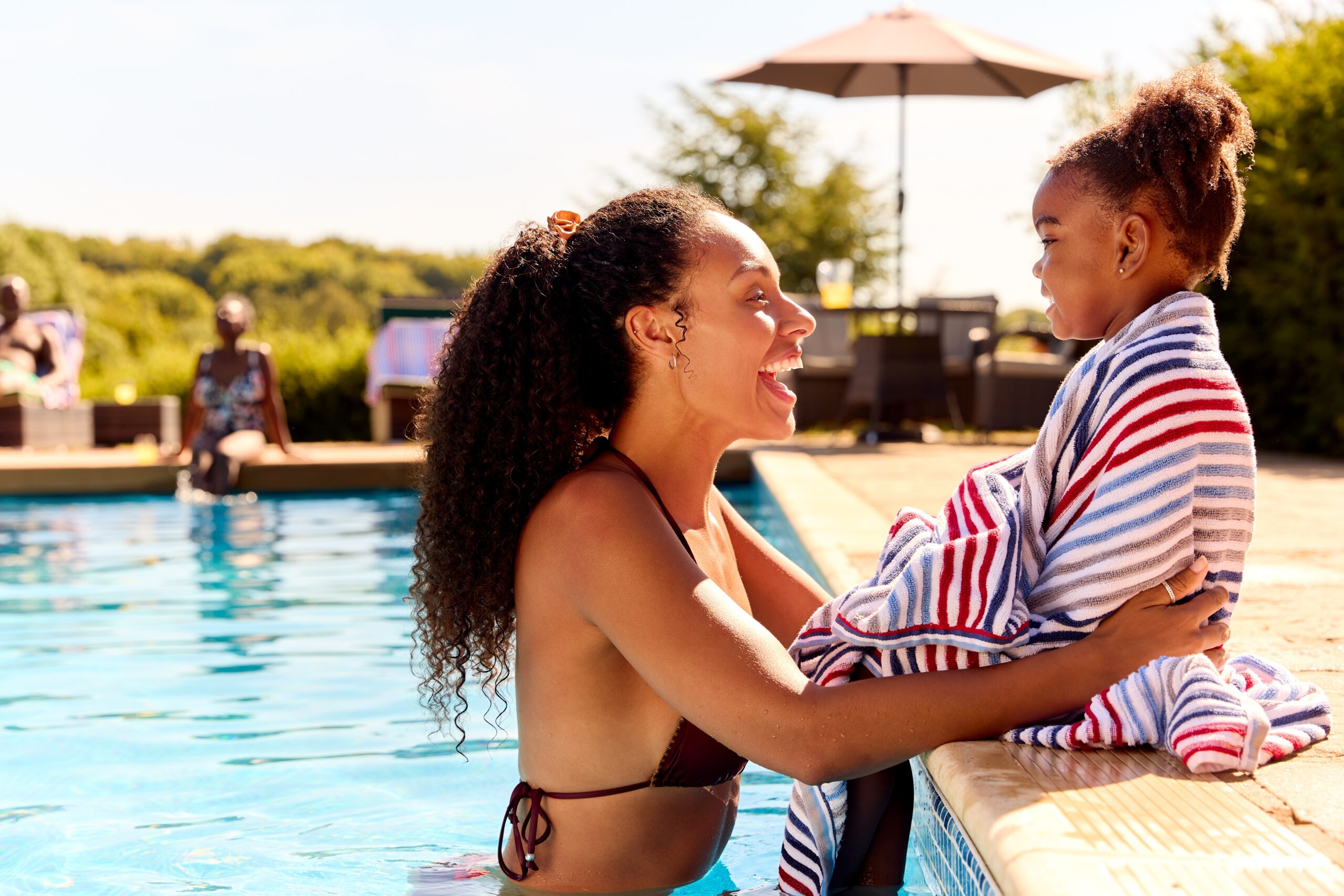 A woman with her daughter enjoying time by the pool.