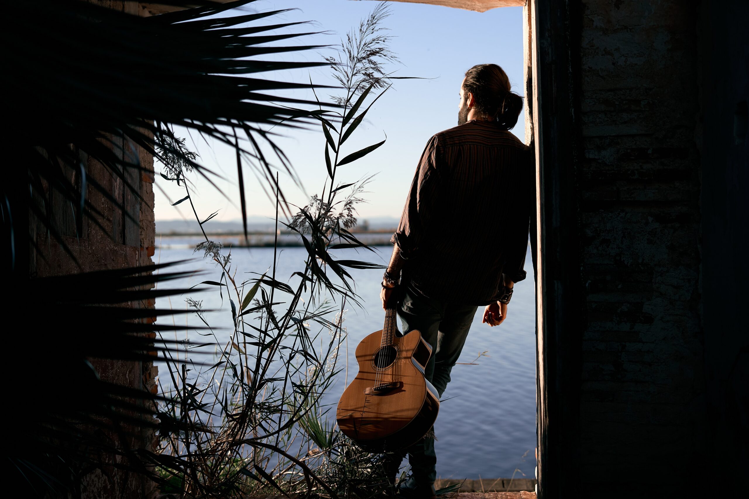 A lonely man playing guitar on his own.